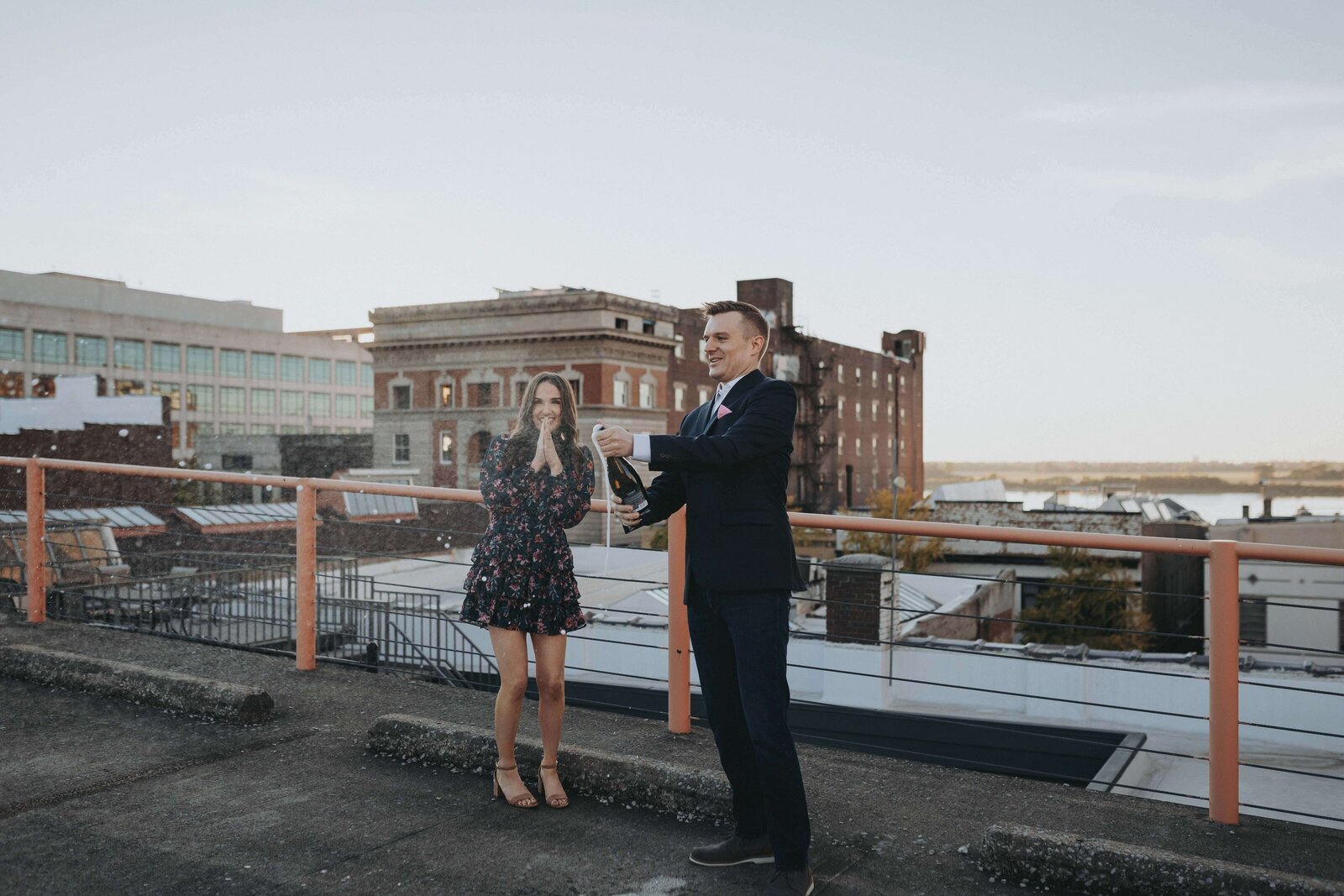 Engaged and popping champagne on a rooftop at sunset!