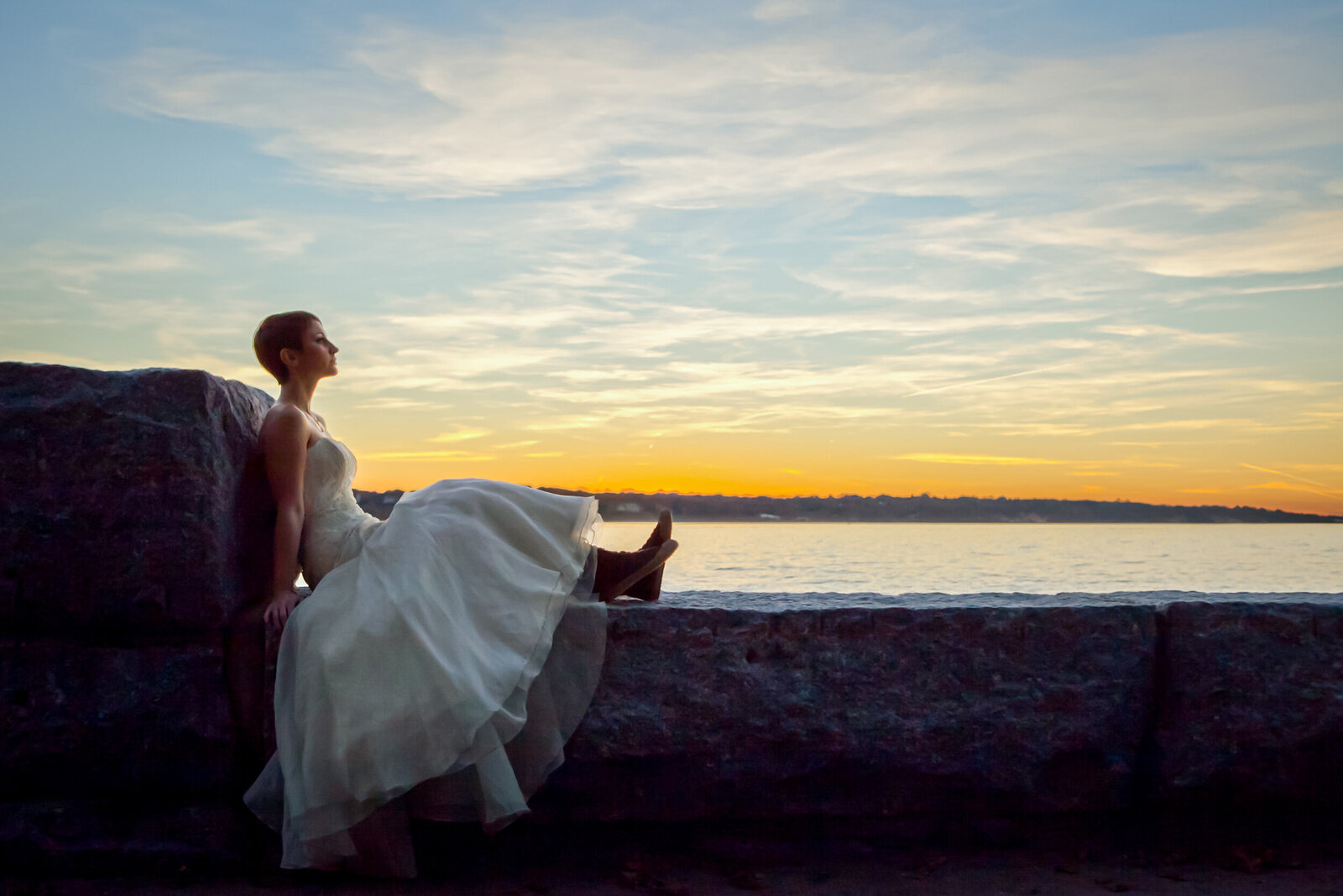 a bride sitting in front of a sunset