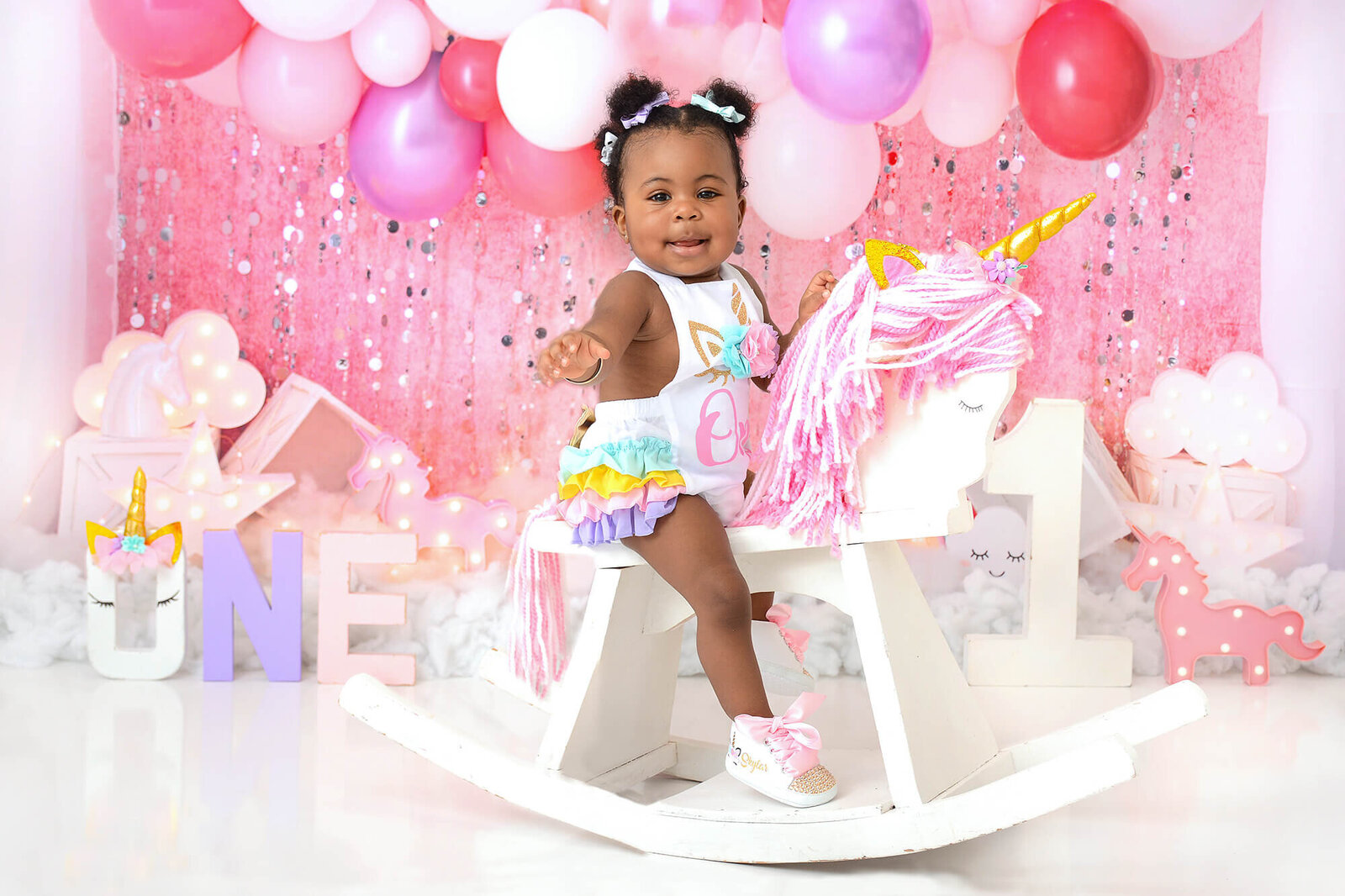girl smiles at her girly unicorn themed first birthday photoshoot