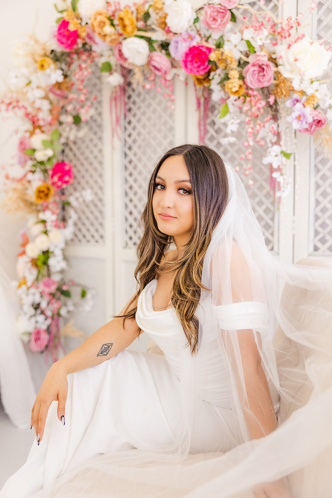Bride posing in a beautiful setting with soft floral decorations, showcasing her elegant wedding dress and radiant beauty for a memorable bridal portrait.