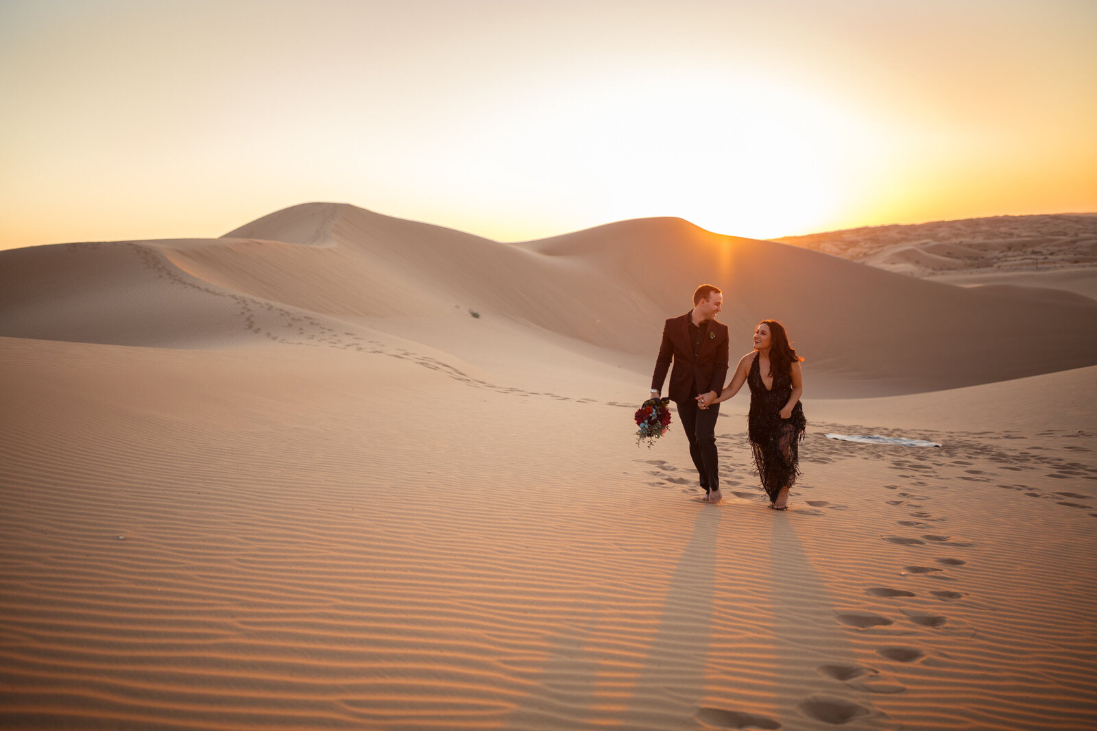 couple walking through massive sand dunes