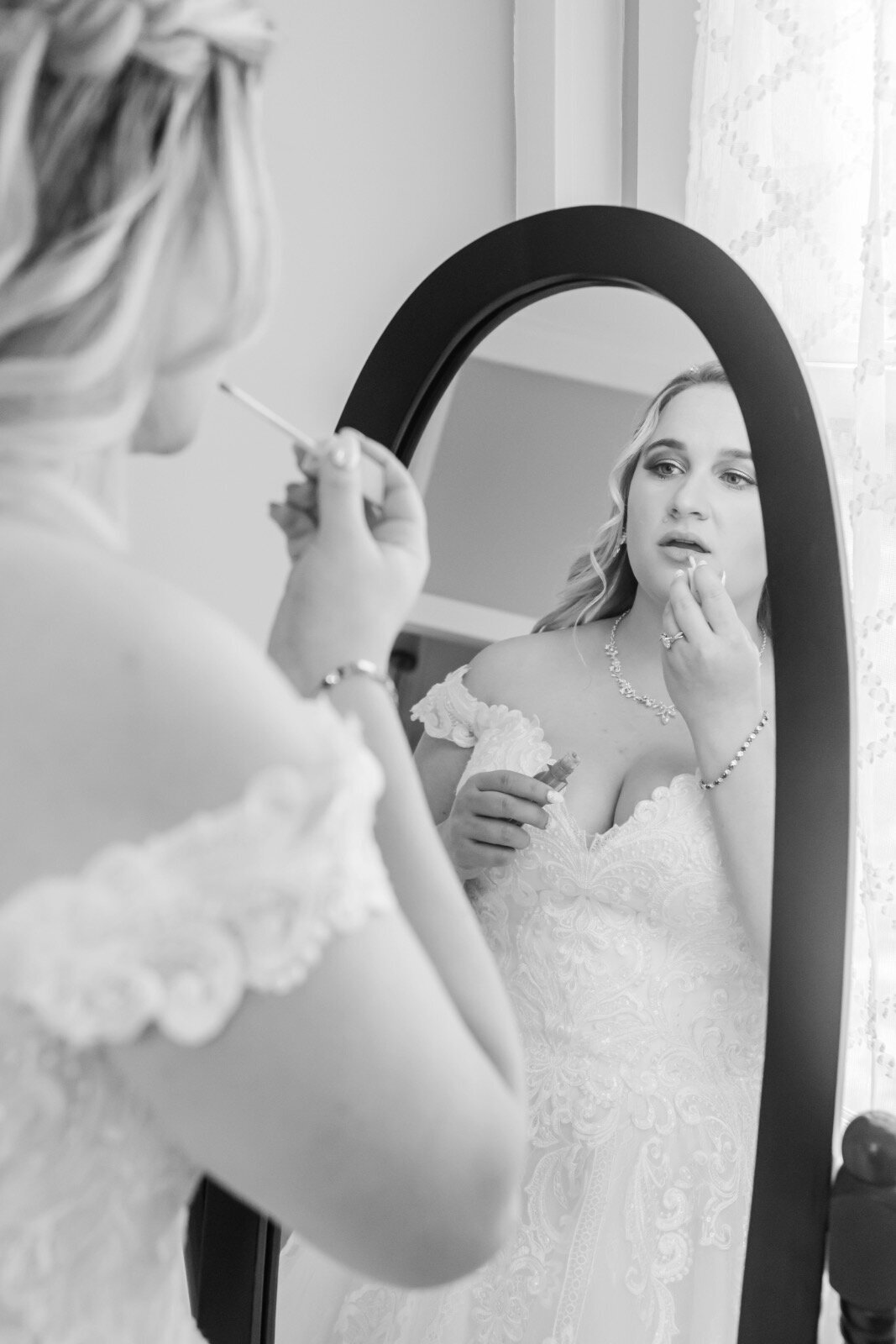 Bride putting on lipstick in the mirror