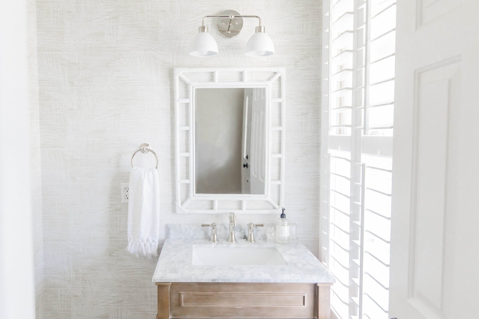 Small bathroom design with white vanity, woven wallpaper, and chrome fixtures styled by KASL Design Co.