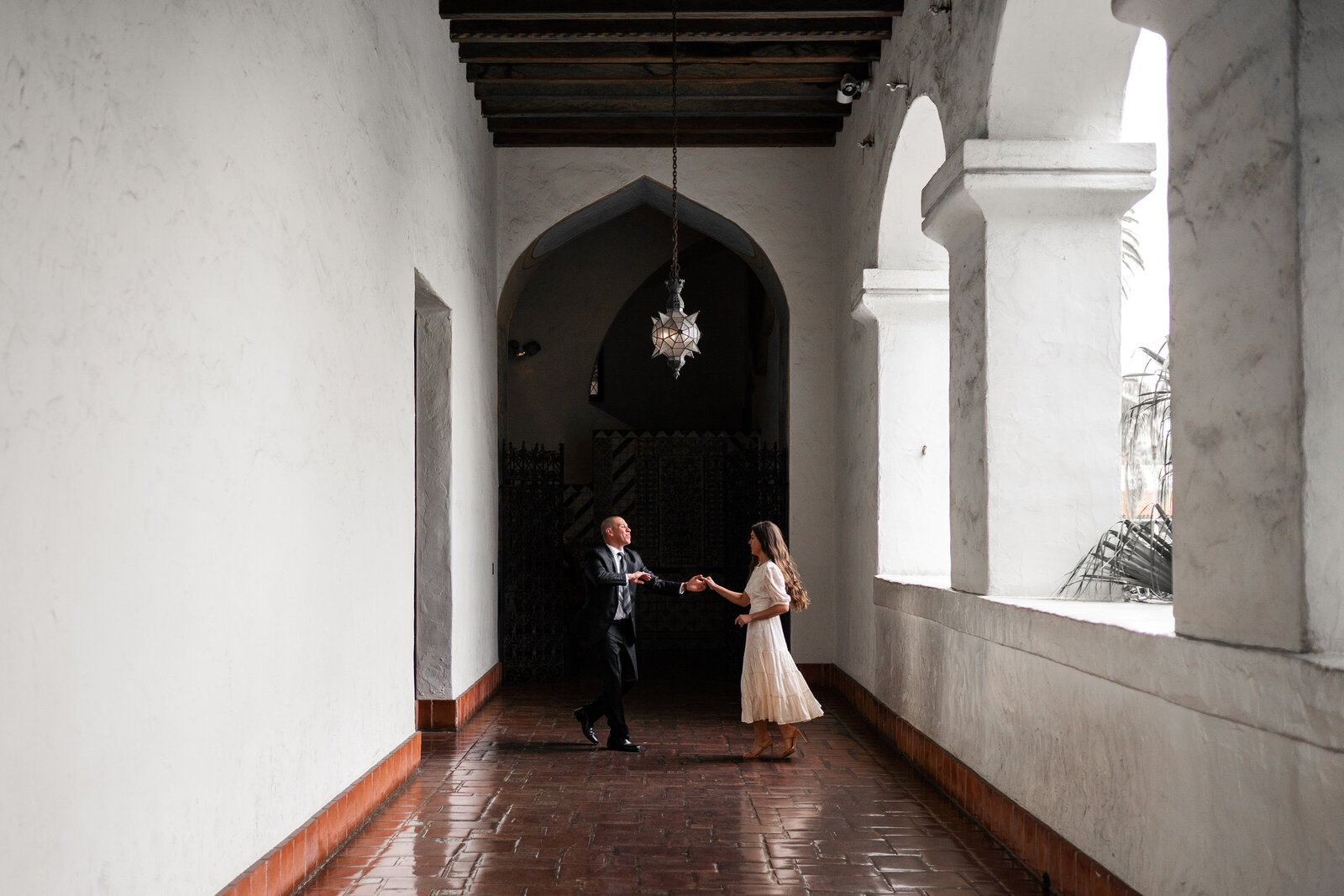 Couple dancing in long hallway in their wedding attire.