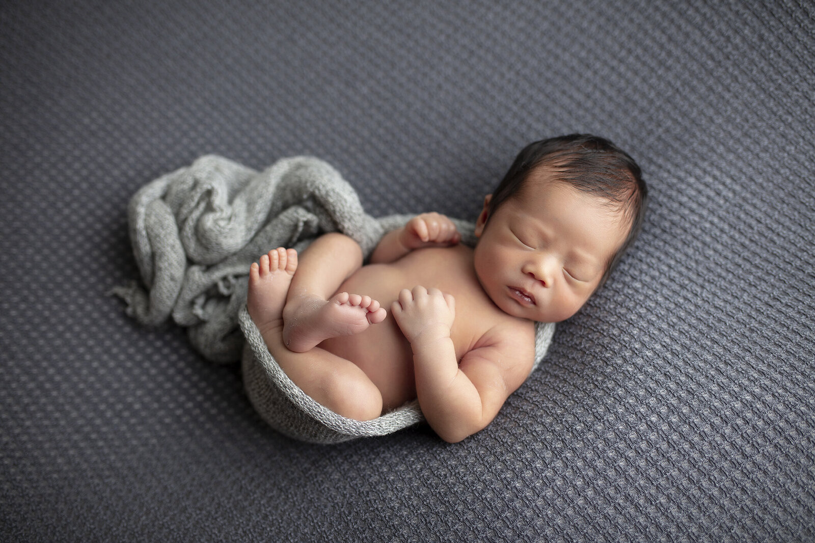 Newborn boy on grey fabric in Dallas, Texas.