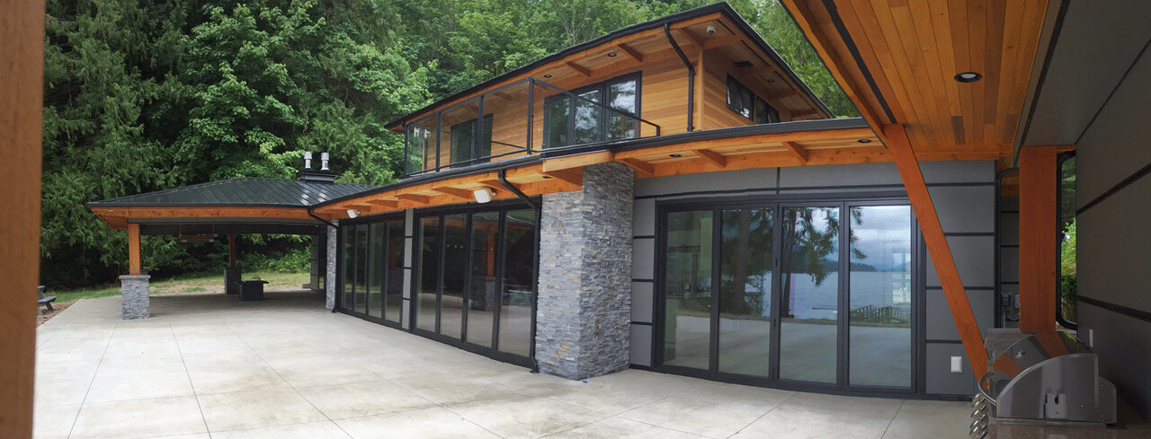 Modern west coast home design exterior with cedar, stone, and glass patio doors