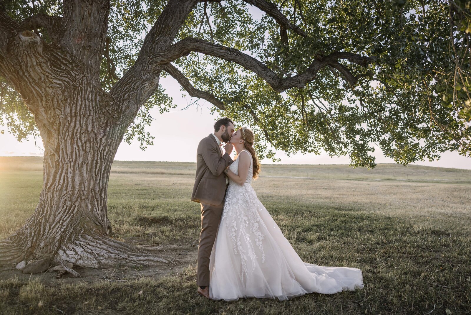 bride and groom kissing under a cottonwood tree