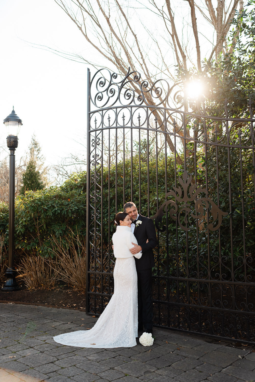 bride and groom in front of elaborate gate with sun 