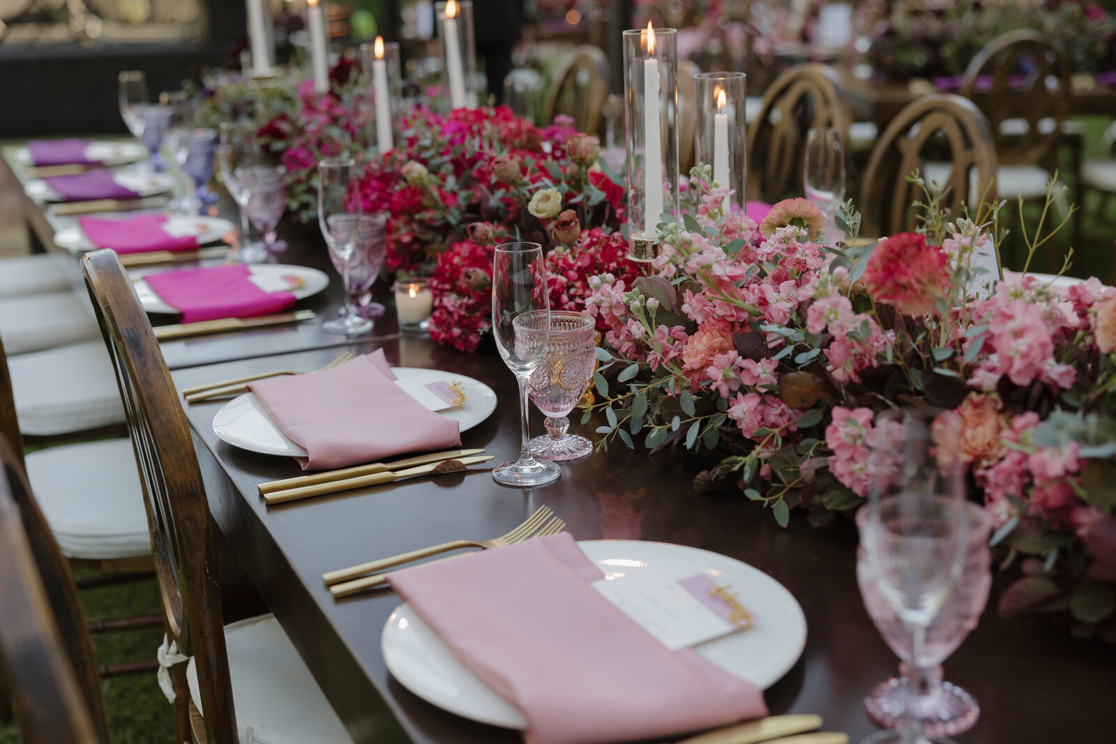 A beautiful reception table of dark and light pinks with candles lit across the table. It was an ombre of pinks. 