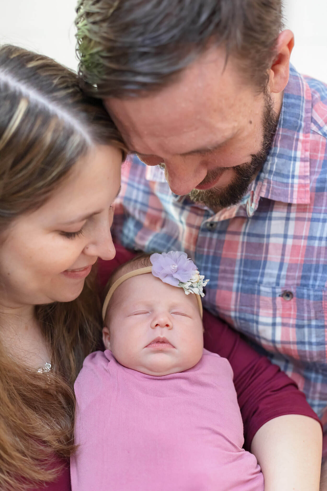 A close-up of a Manassas newborn girl with mom and dad smiling down at her.