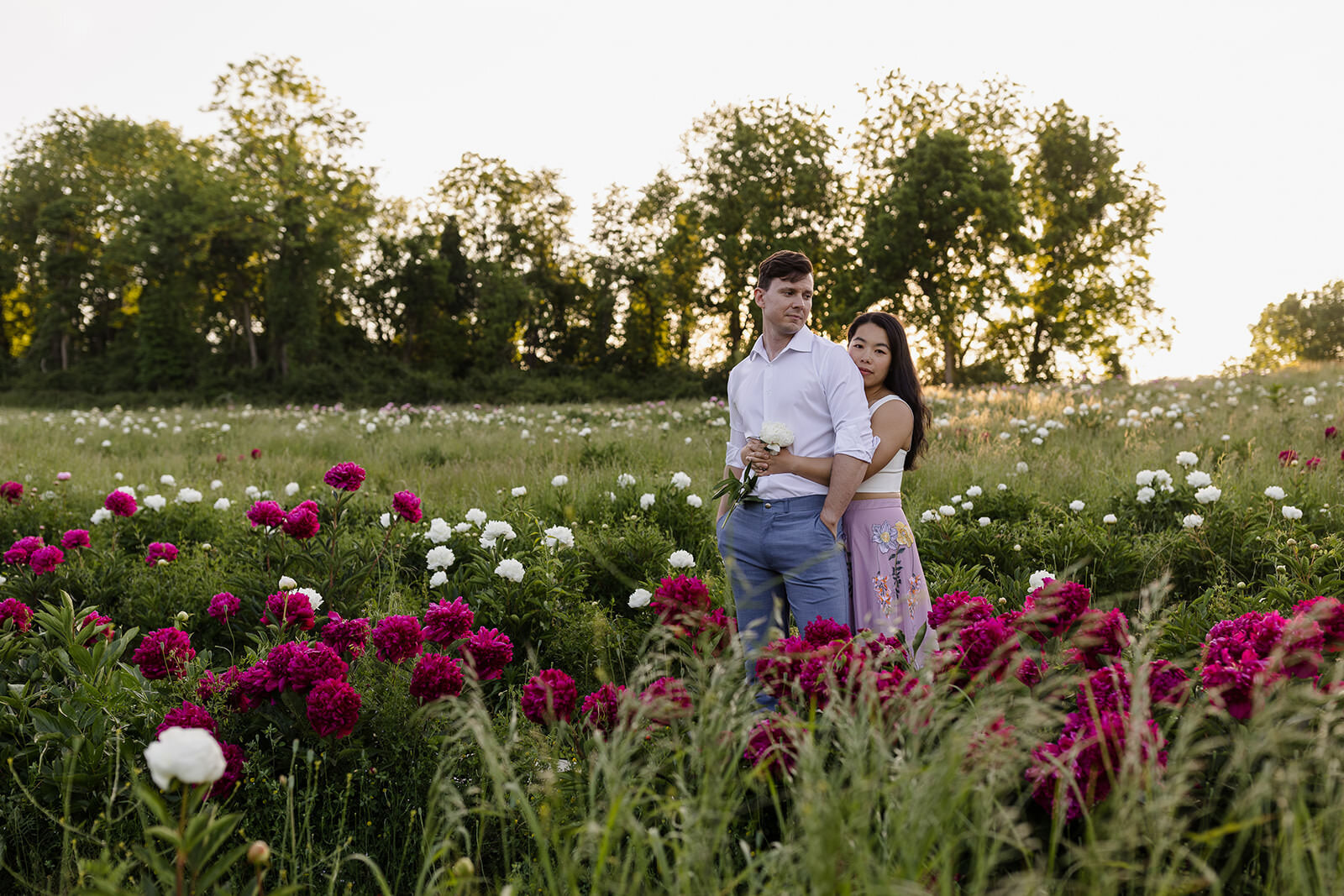 A couple stands in a field of blooming peonies in Kennet Square
