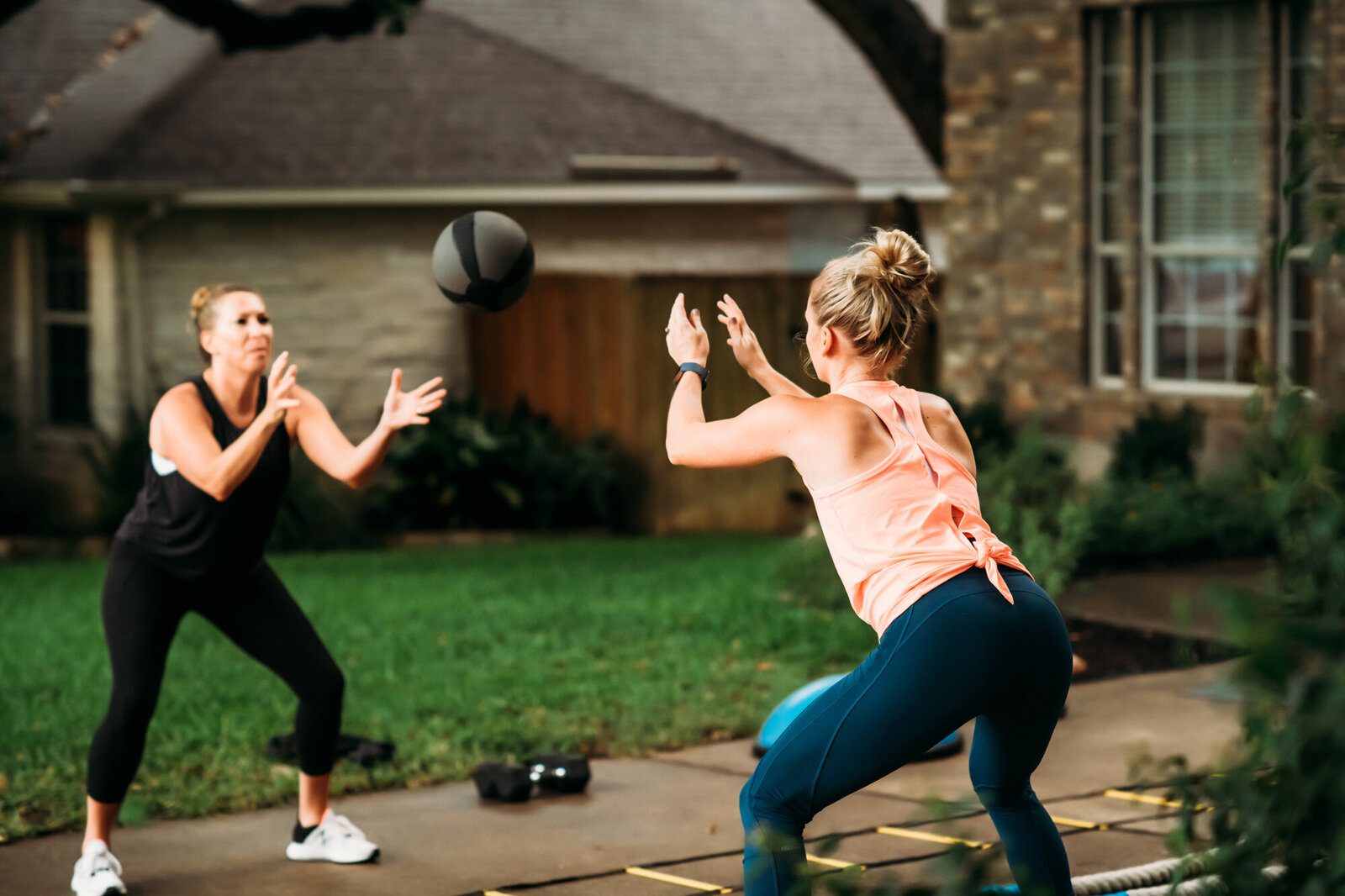 Branding Photographer,  two women toss a weighted medicine ball in their front yard