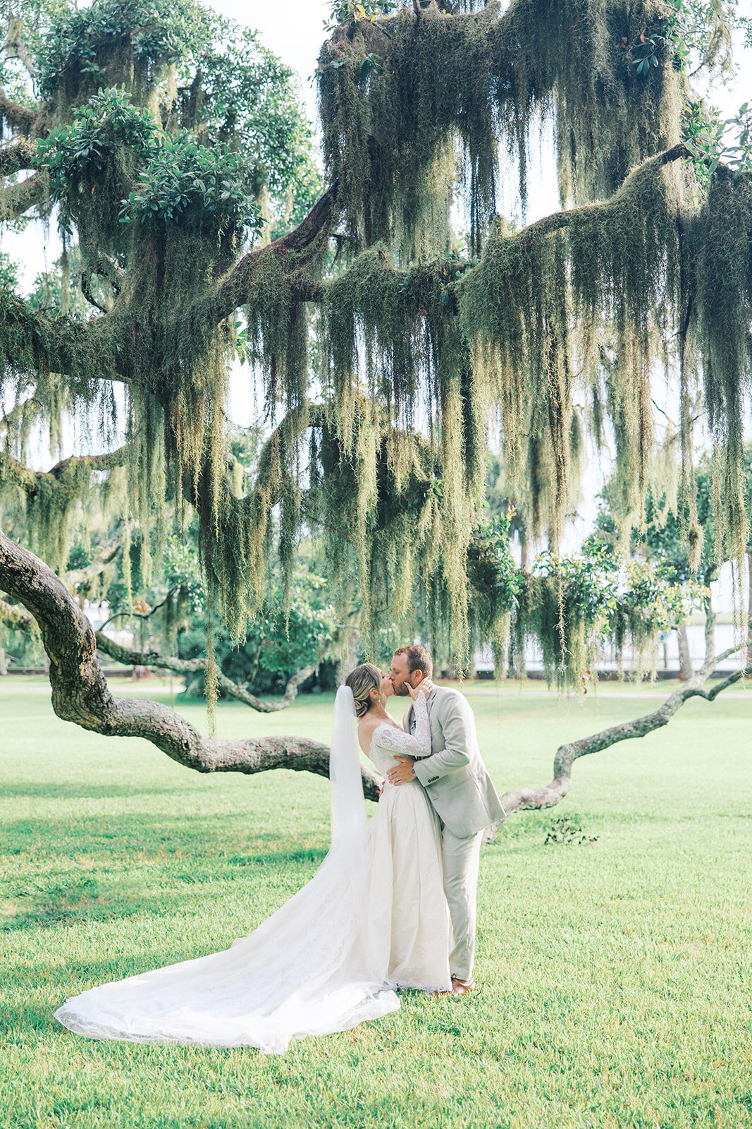 Bride and Groom kiss under the green mossy oaks at their wedding on the coast of Georgia at Jekyll Island Club resort