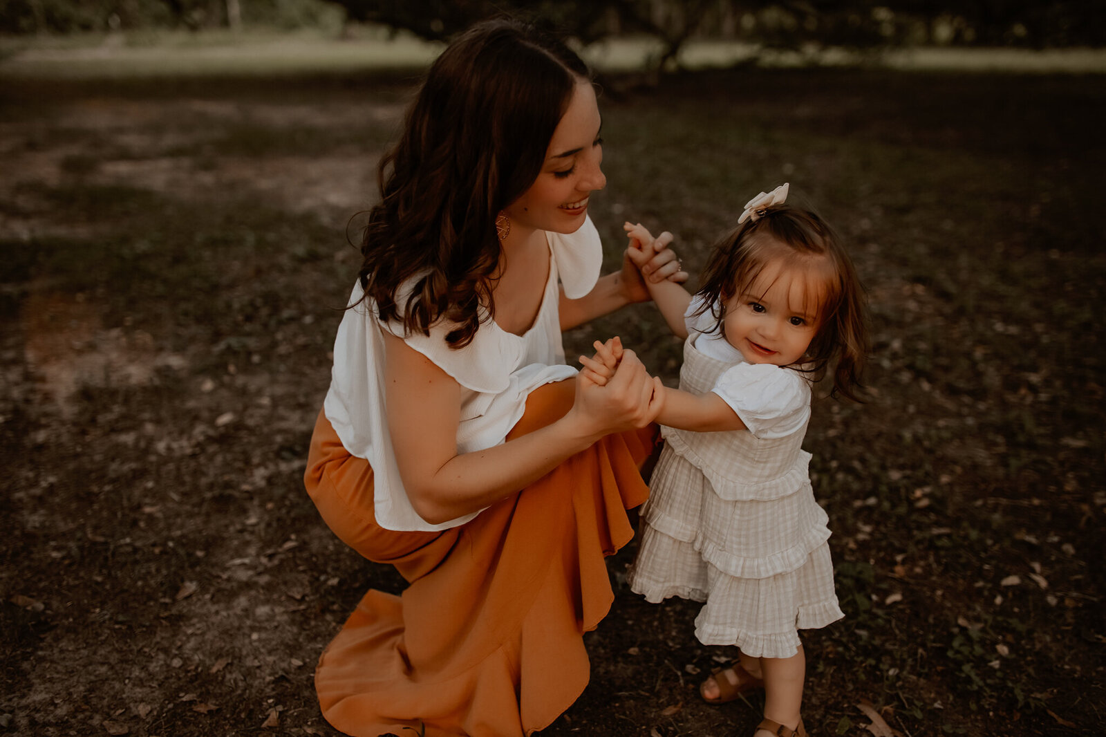 Family photography near Livingston TX - mother kneeling and playing with toddler daughter outdoors during candid session