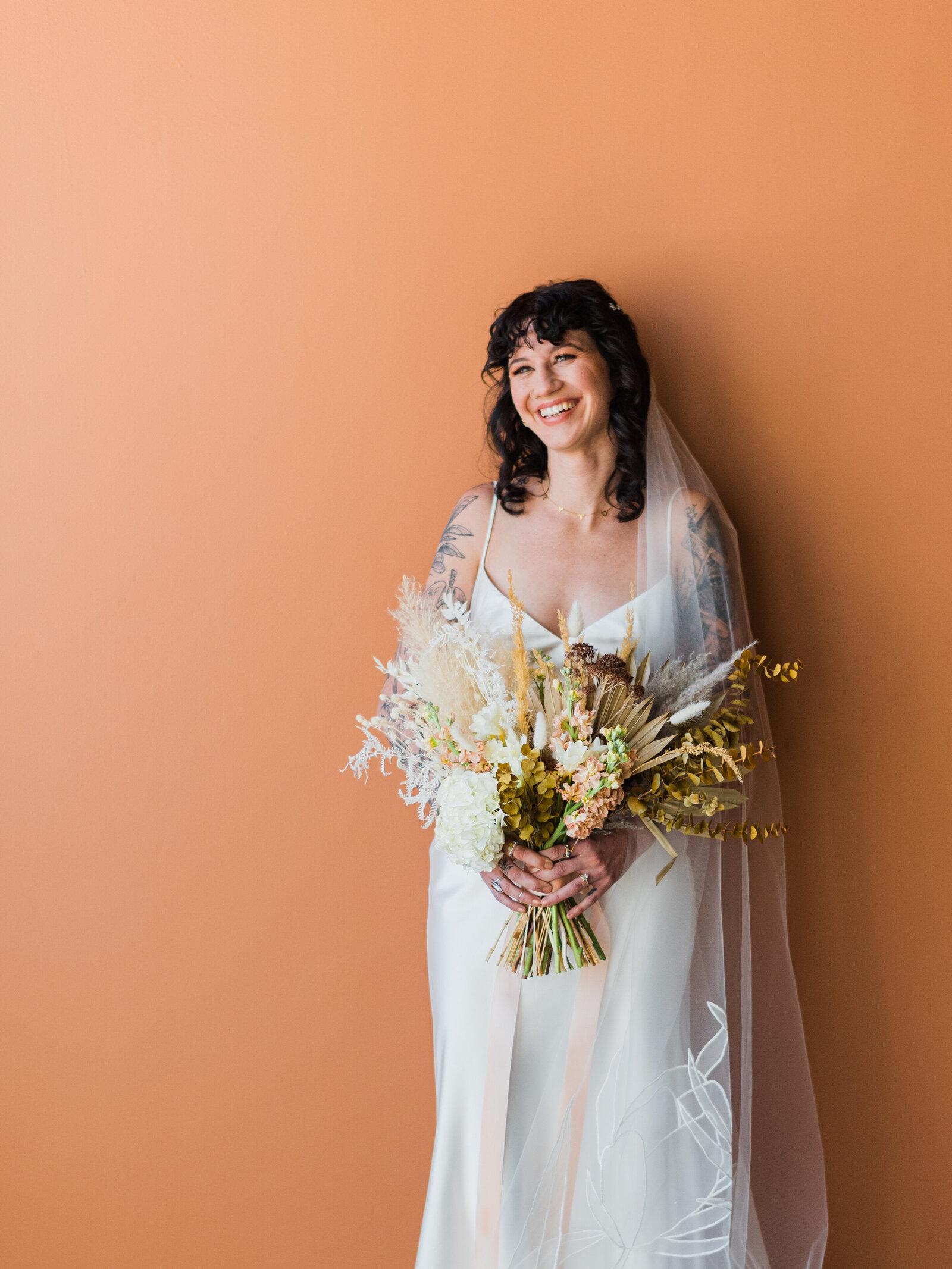 Bride laughing with bouquet of flowers