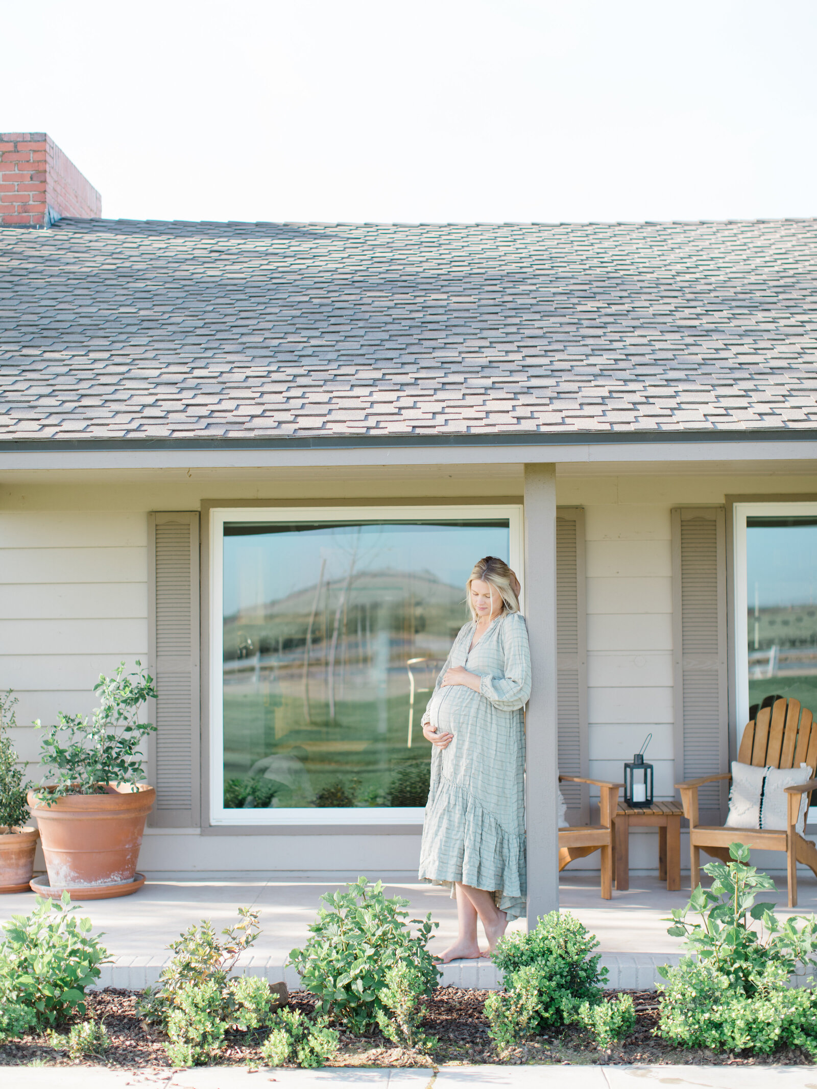 pregnant mother on a porch holding her pregnant belly and smiling