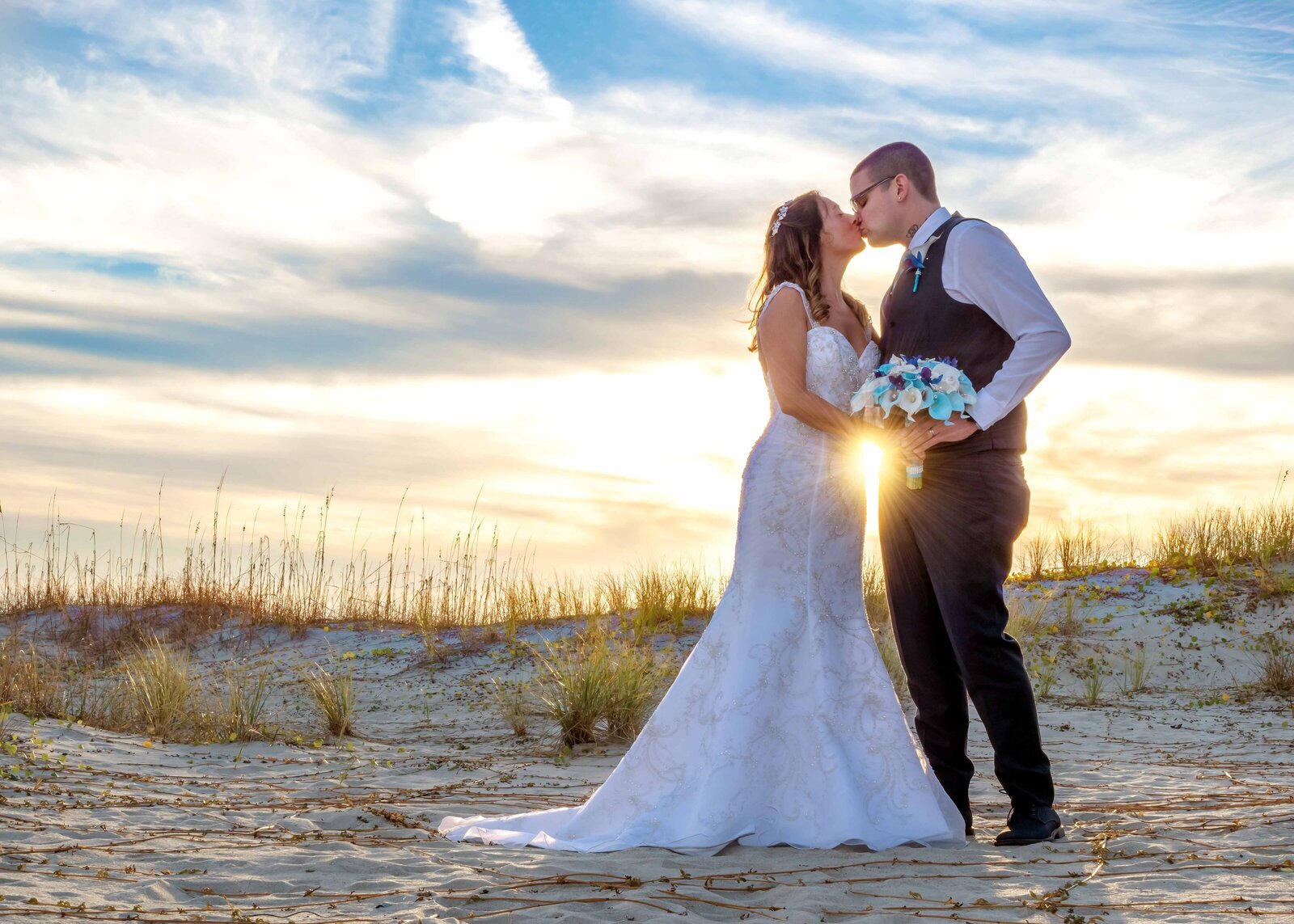 Bride and groom sharing a romantic kiss at sunset on the beach, capturing the magic of their wedding day in In Ocean Isle Beach, North Carolina.