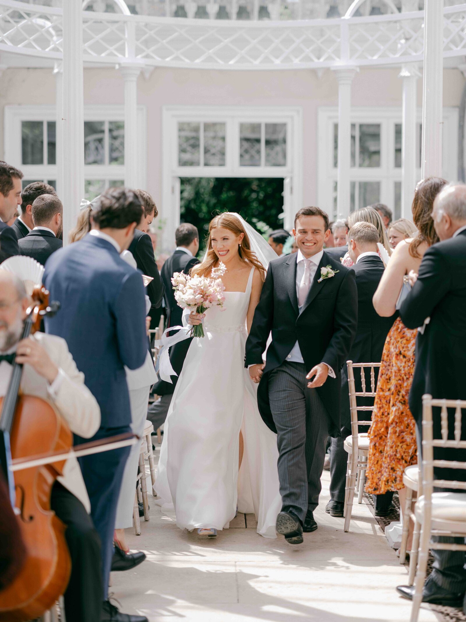 Bride and groom waling down the aisle in the came house conservatory dome