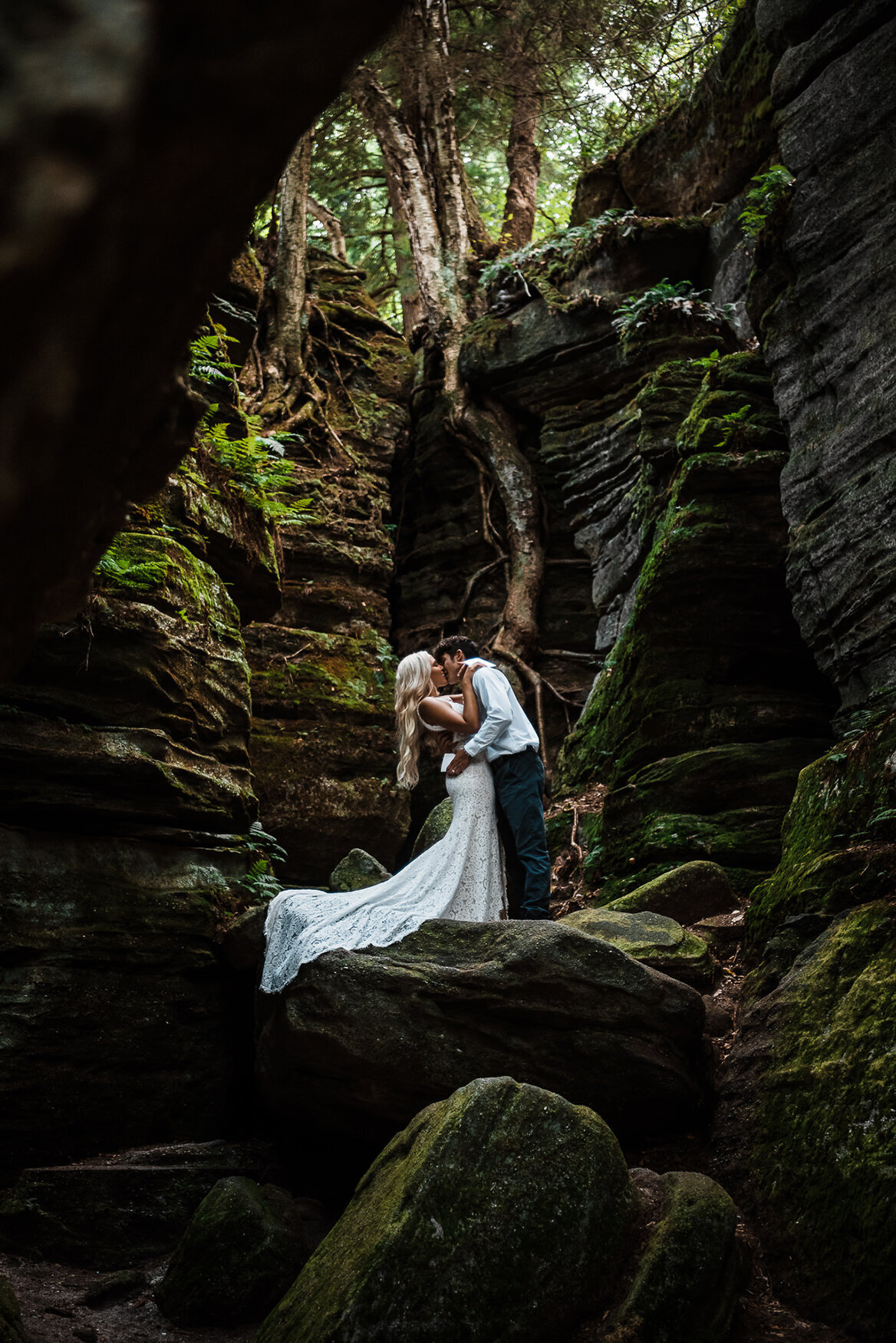 bride and groom kiss on rock