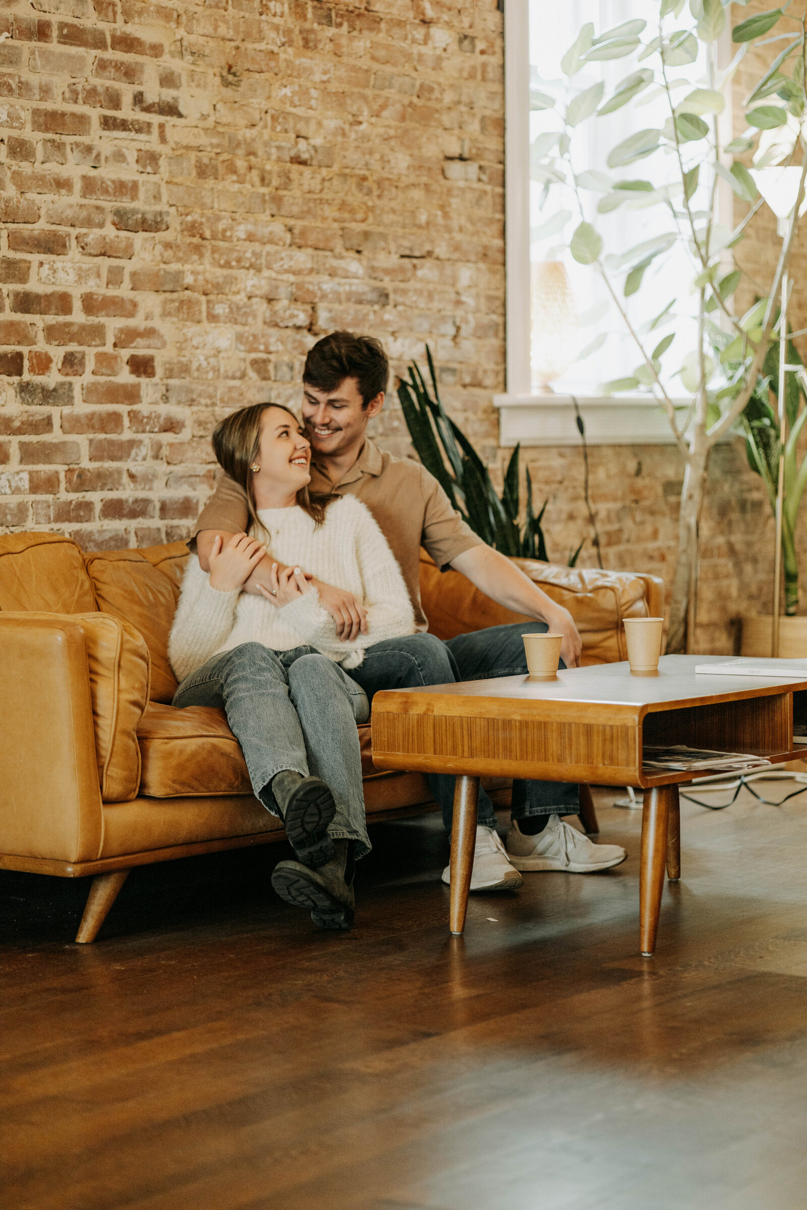 Megan and Luke snuggled up on a leather couch during their coffee shop engagement session at Comeback Coffee in Memphis, Tennessee.