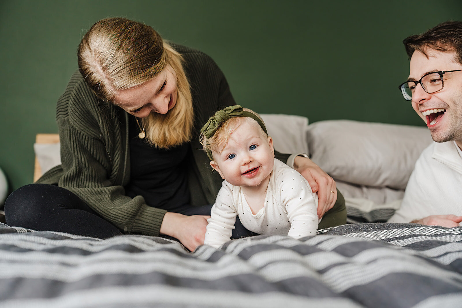 six month old baby smiles at camera from parents bed