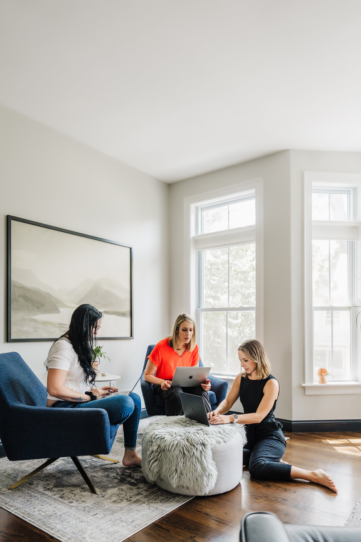 team of three women work together in a neutral living room