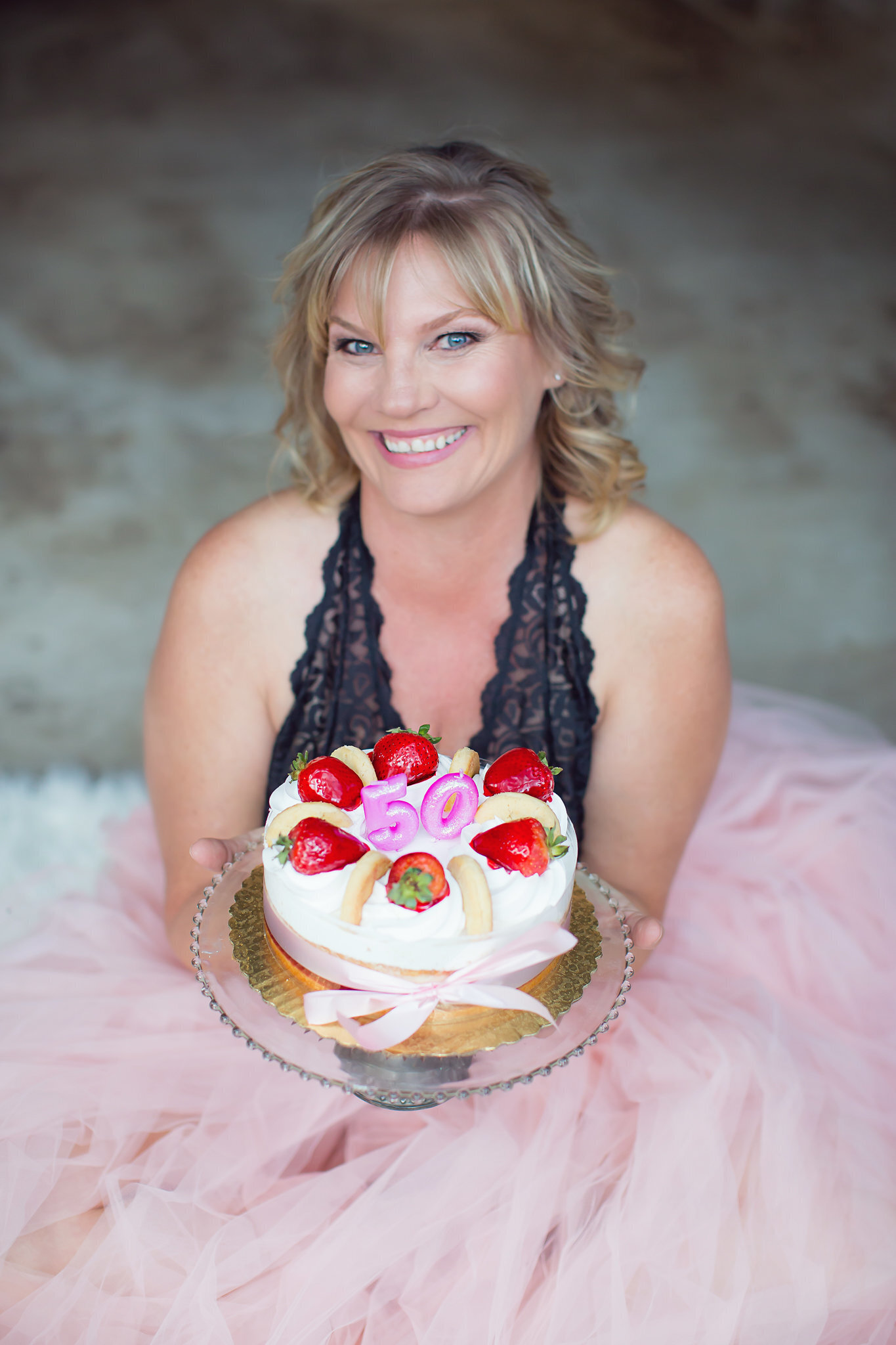 Woman holding strawberry cake in lace budoir  top and pink skirt