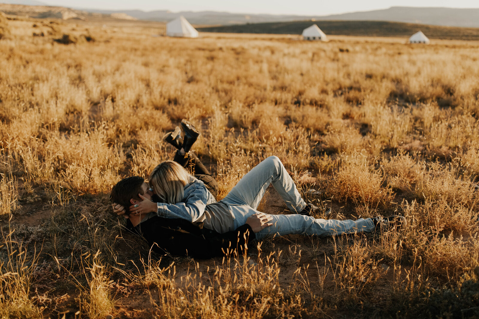 Engagement session with couple kissing laying in field