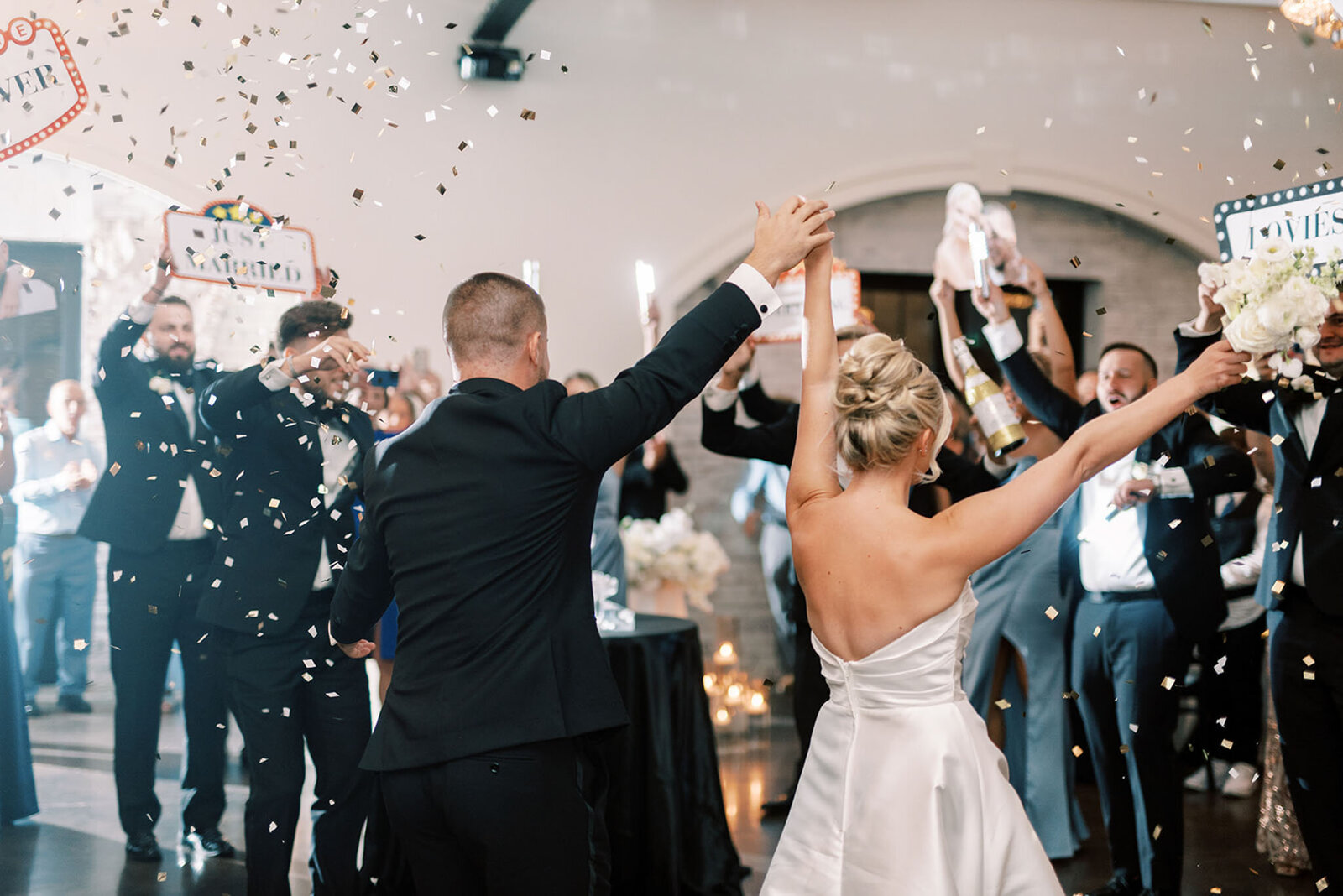 guests joyfully waving and throwing confetti welcoming the  bride and groom at Grbic Events, a wedding venue in St. Louis.