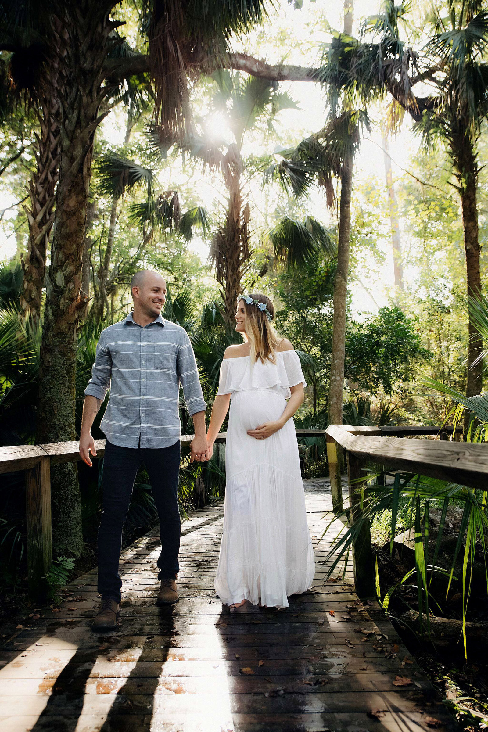 A pregnant woman poses with her husband in a beautiful park, captured by Bia Schaefer Photography.