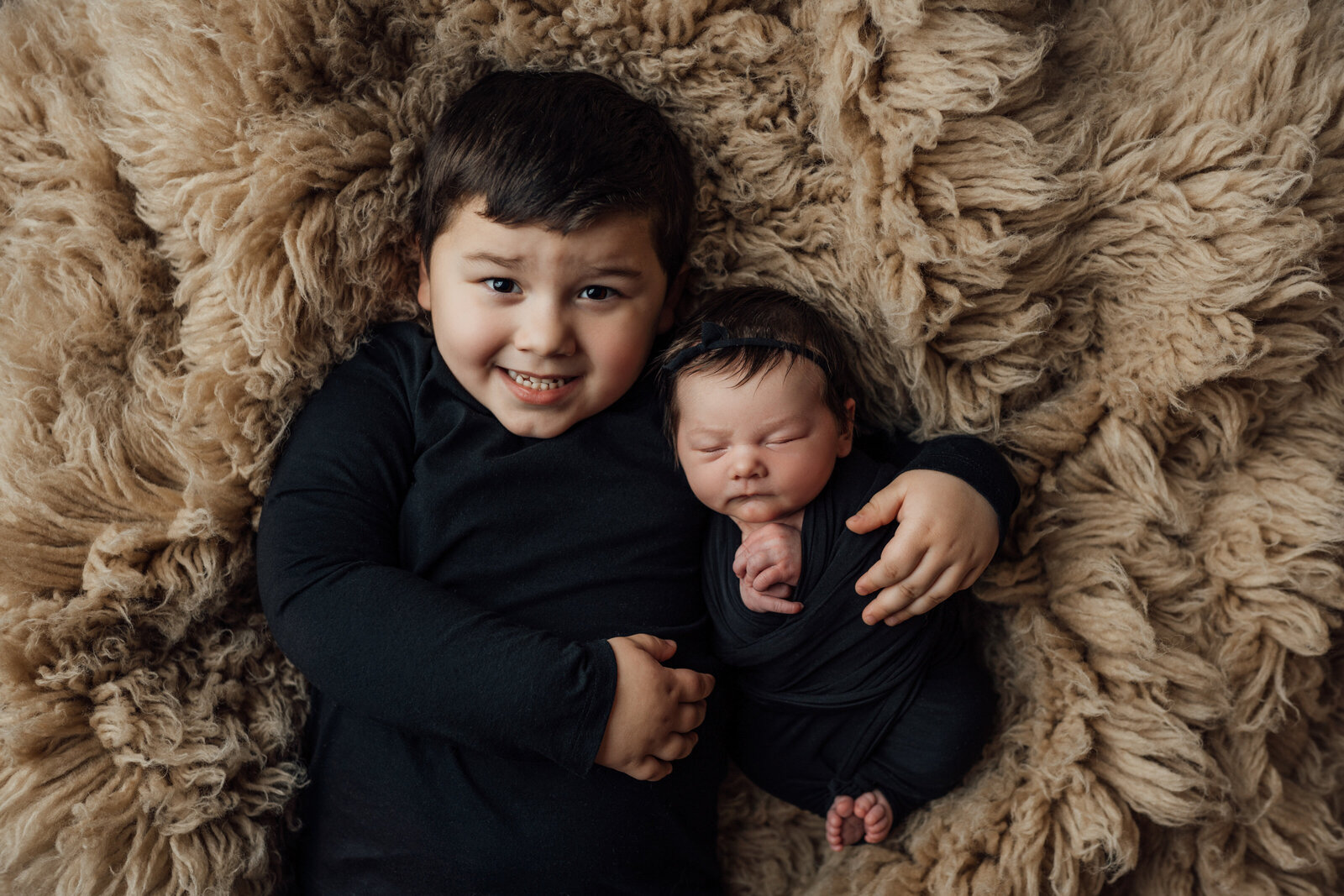 siblings pose for newborn session at studio in Lutz