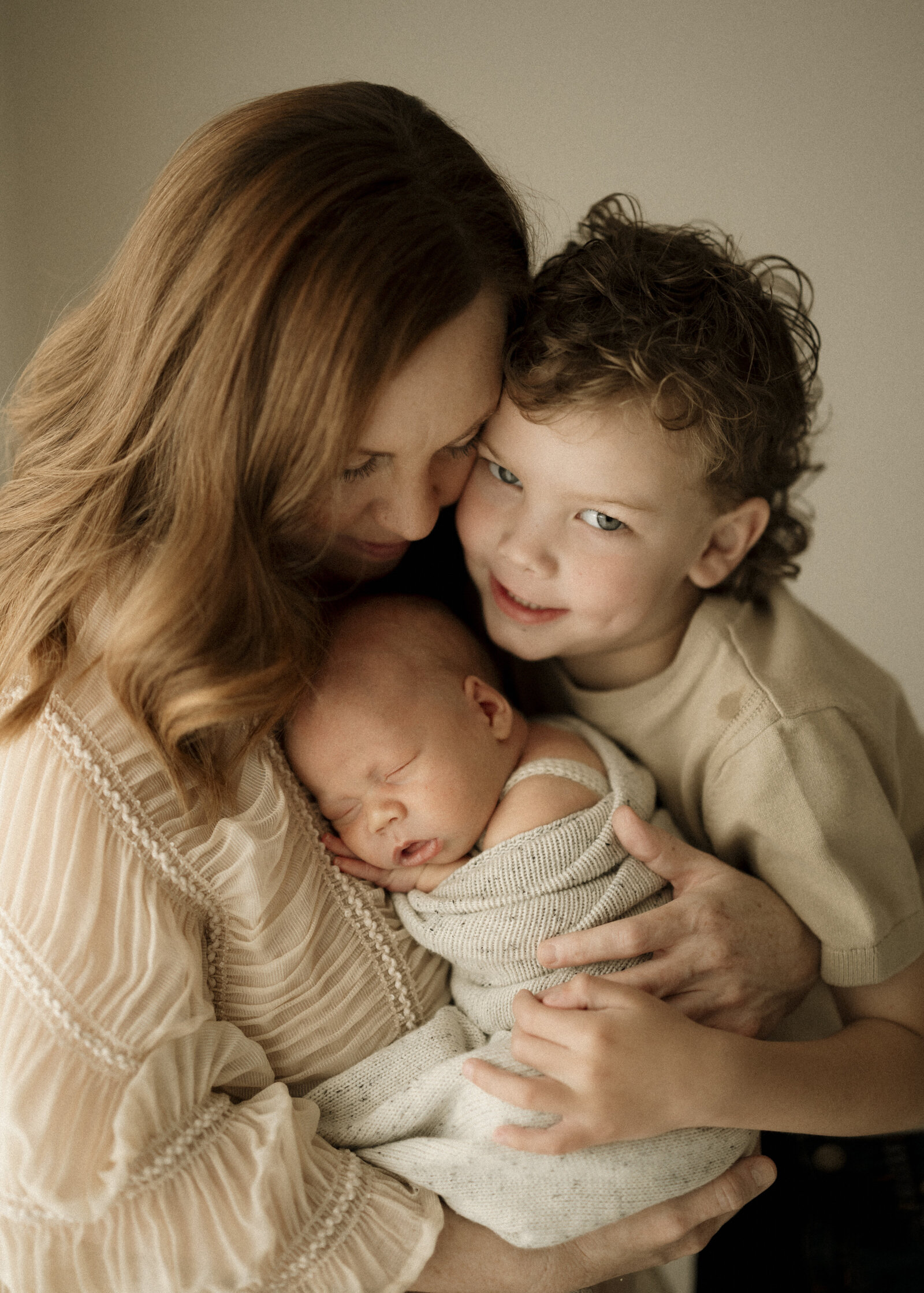 Studio newborn family photography in Perth – a beautiful, intimate portrait of new parents holding their baby in soft natural light.