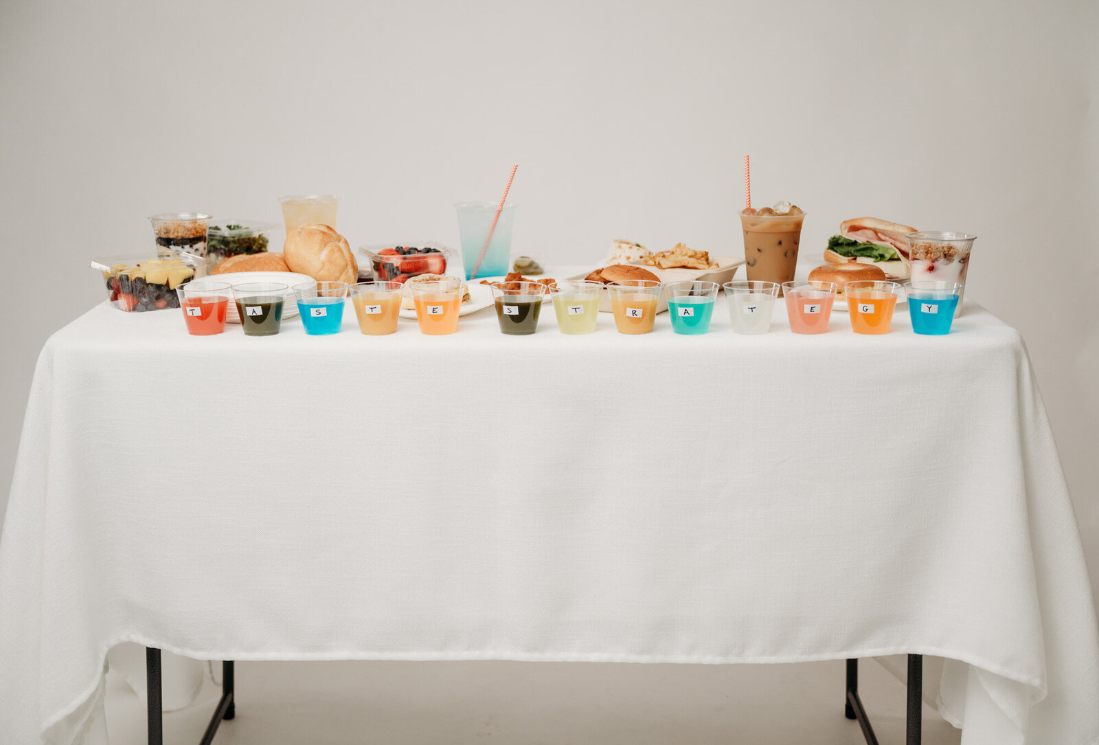 colorful drinks spelling out "Taste Strategy" on a table full of food