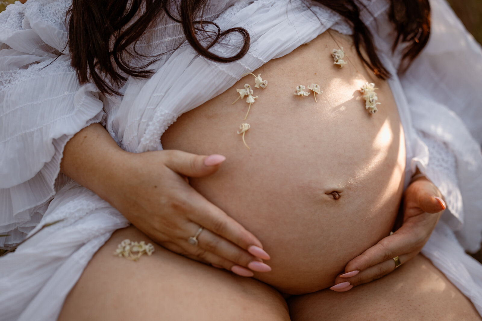mother holding her baby bump, flowers covering the bump for a creative and loved up look