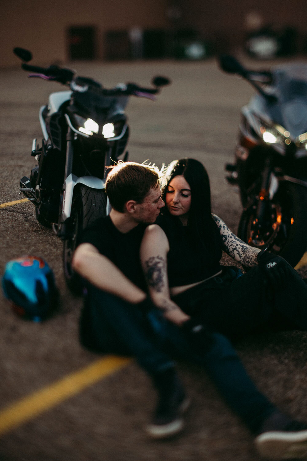 Alternative couple sit in front of bikes in parking lot