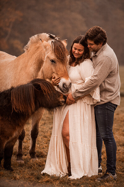Een stralende aanstaande moeder poseert met haar paard in een serene, natuurlijke setting, die de bijzondere band tussen hen en de verwachting van nieuw leven vastlegt