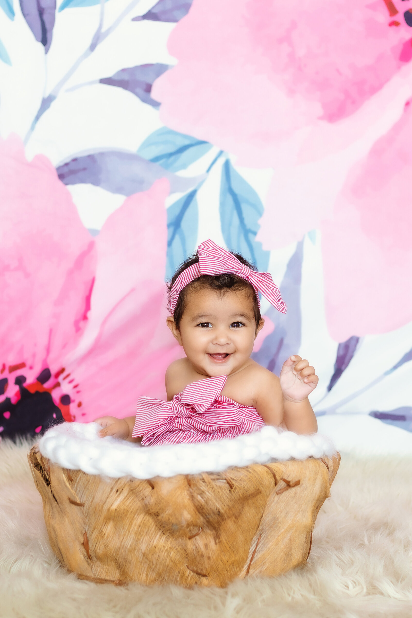 Milestone Photographer, a baby girl with bow in her hair sits in a small basket