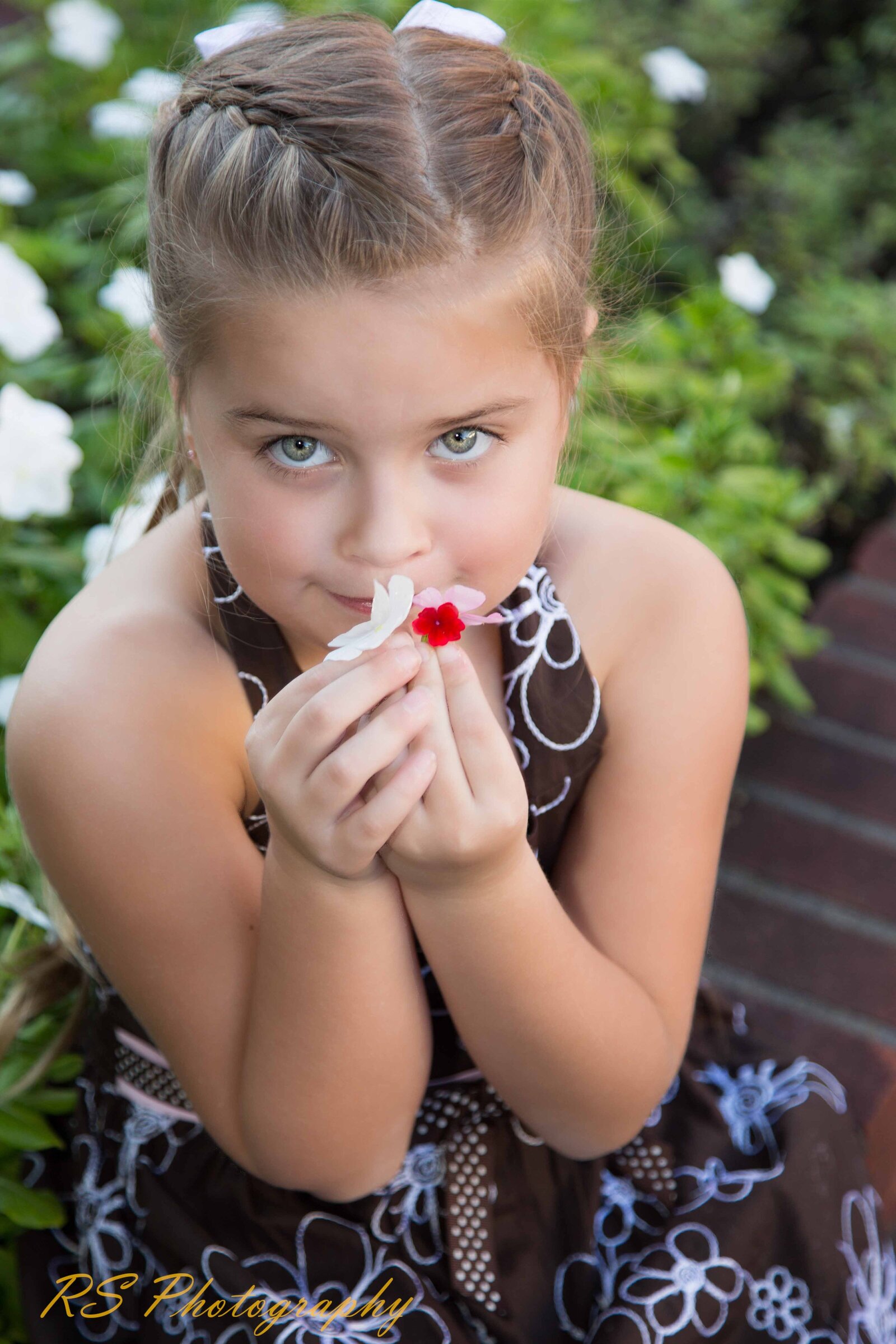 Young lady smelling flower at park with Ron Schroll Photography in Charlotte, NC