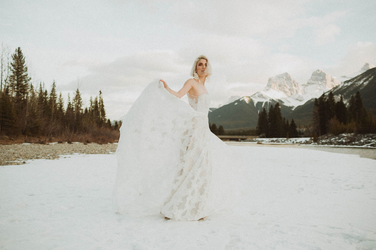 bride in white lace wedding dress walking outdoors with mountains behind