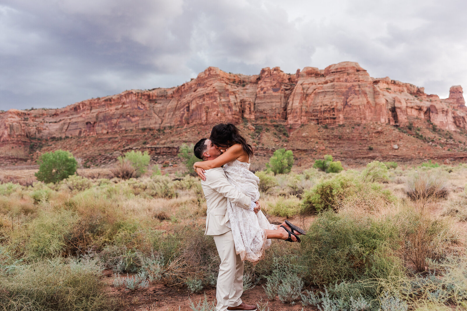 Bride jumping on groom during sunset photos in Moab, UT