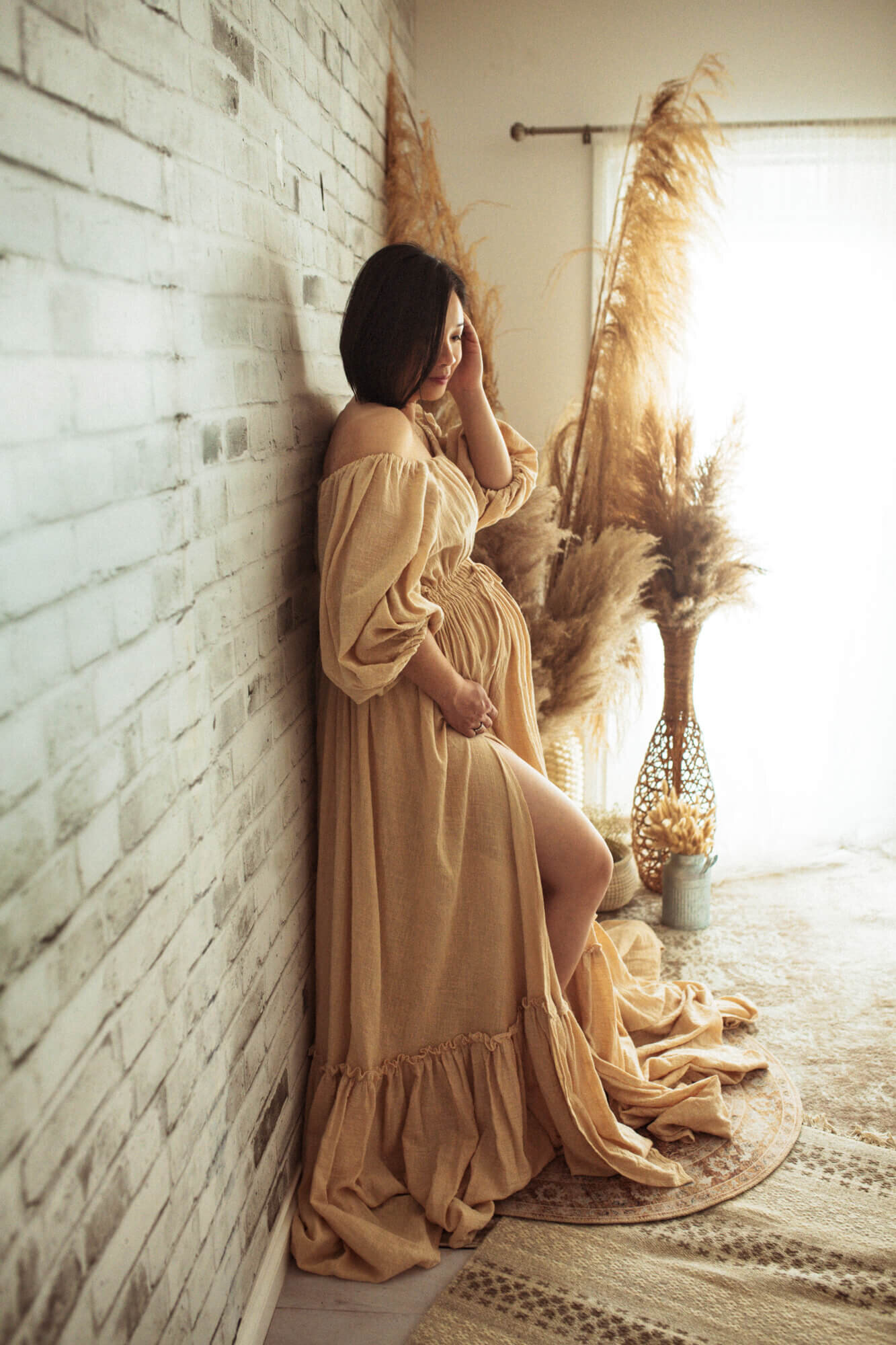 Pregnant woman standing in Reclamation gown with pampas grass