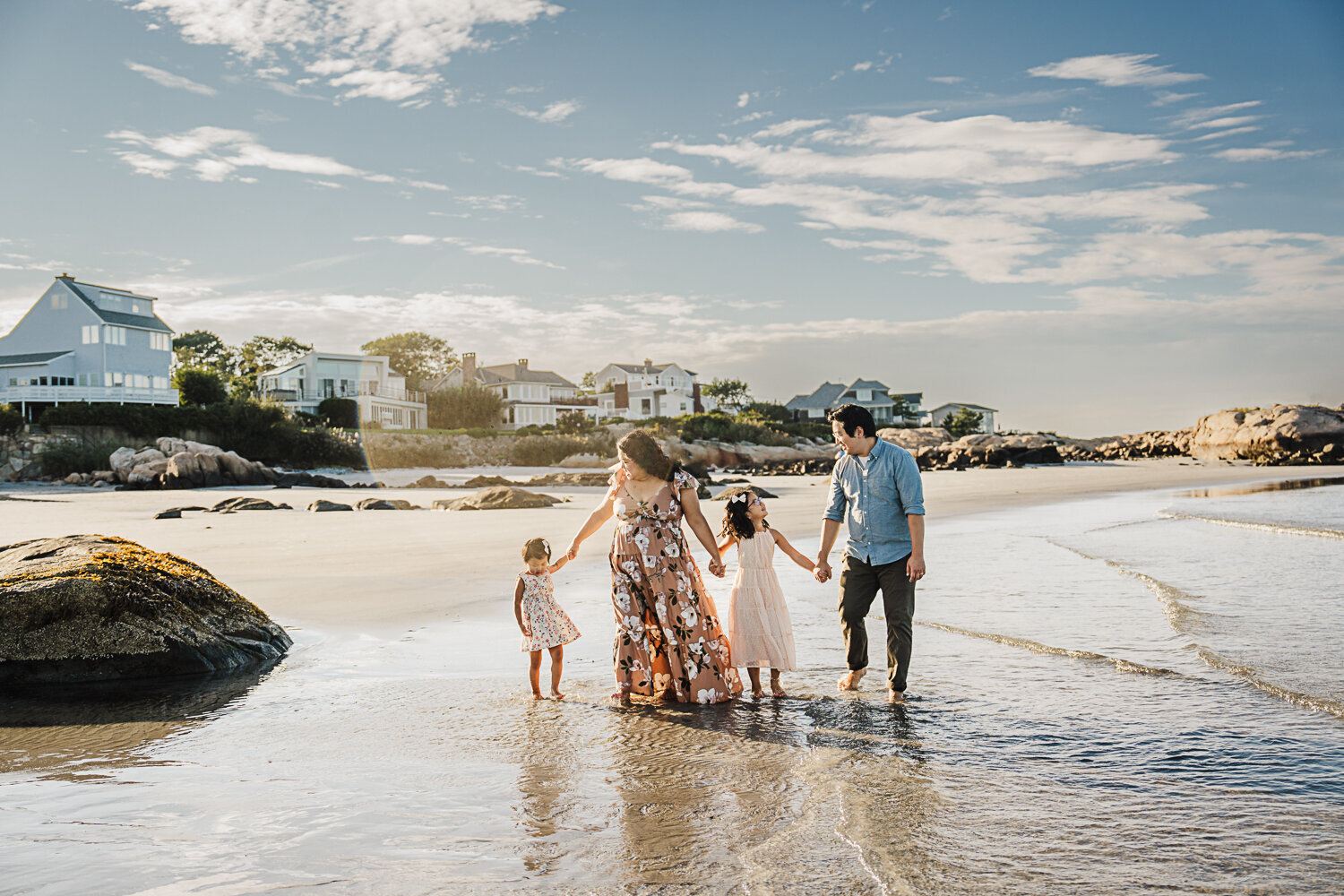 family with two daughters hold hands on north shore boston beach