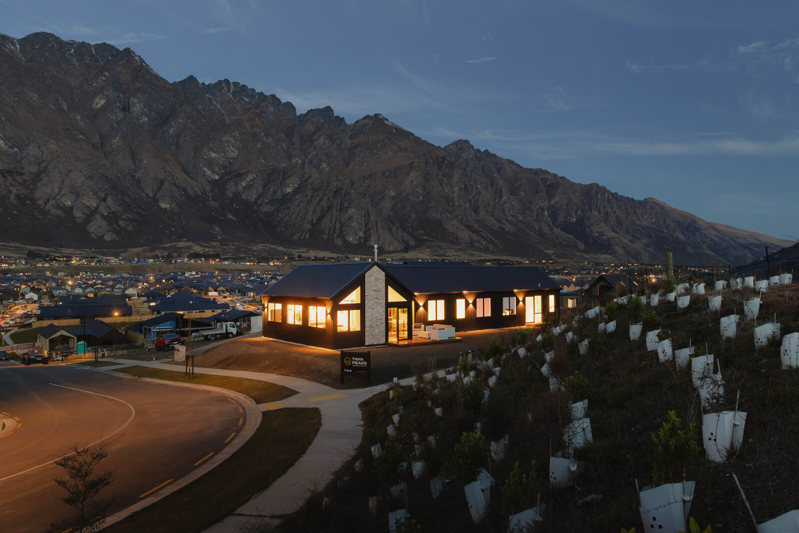 A night view of the exterior of a home featuring timber cladding, brick features and James Hardie Oblique cladding on a home built by Twin Peaks Construction in Hanleys Farm, Queenstown.