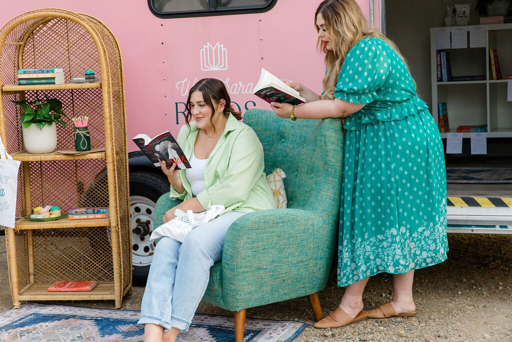 Two women reading outside of the What Sara Reads mobile book trailer