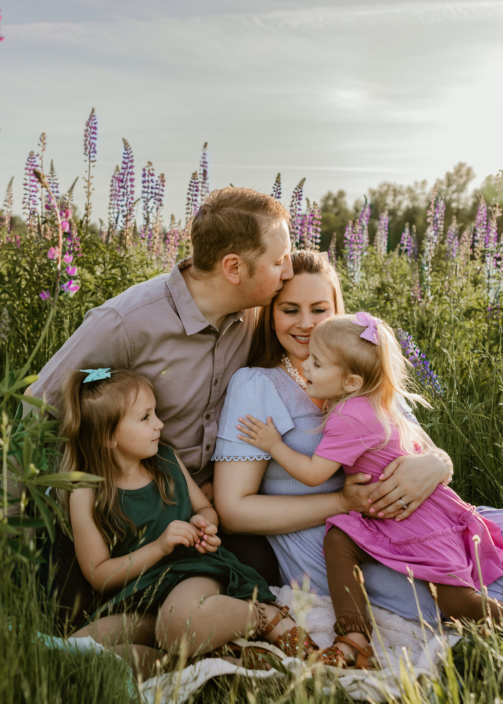 Family of 4 playing in the lupine wildflowers. 