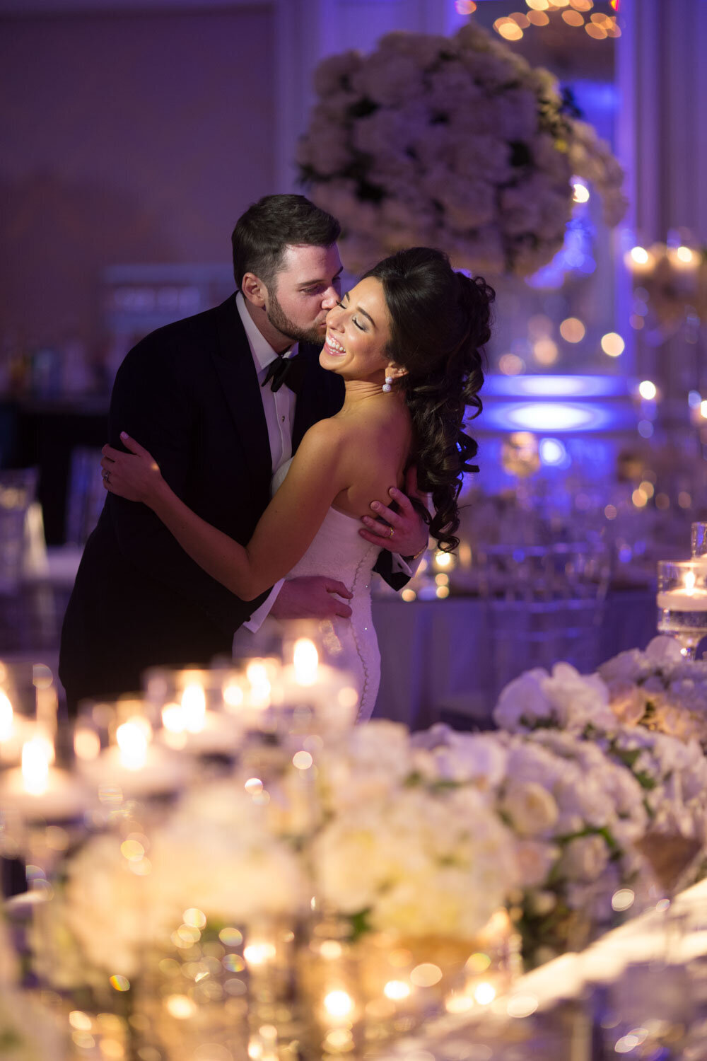 A bride and groom kissing in front of candles and flowers