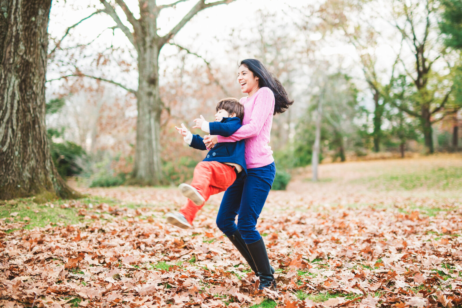 Mom spinning with son in fall leaves