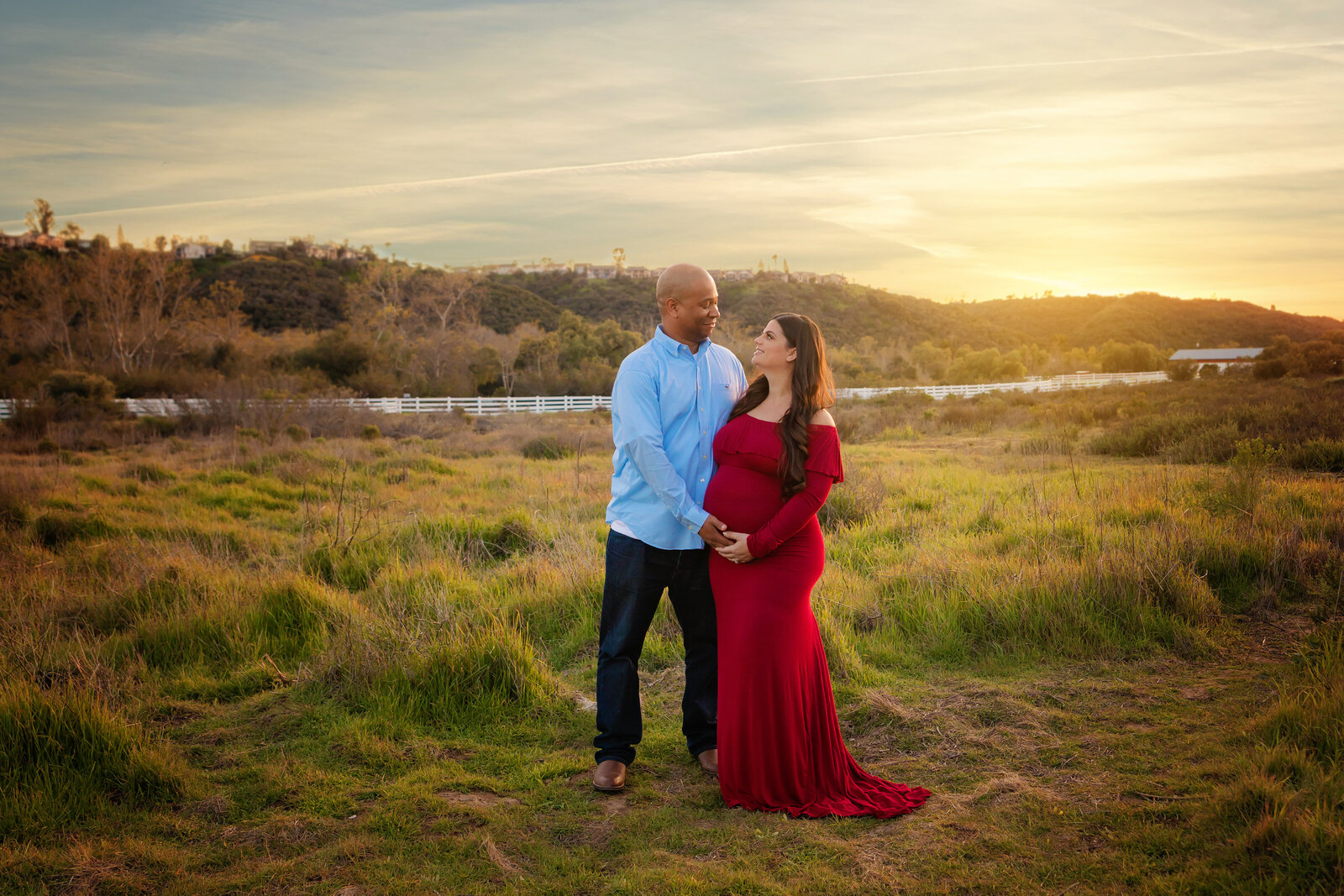 Maternity Photographer, a husband stands with his pregnant wife in a meadow