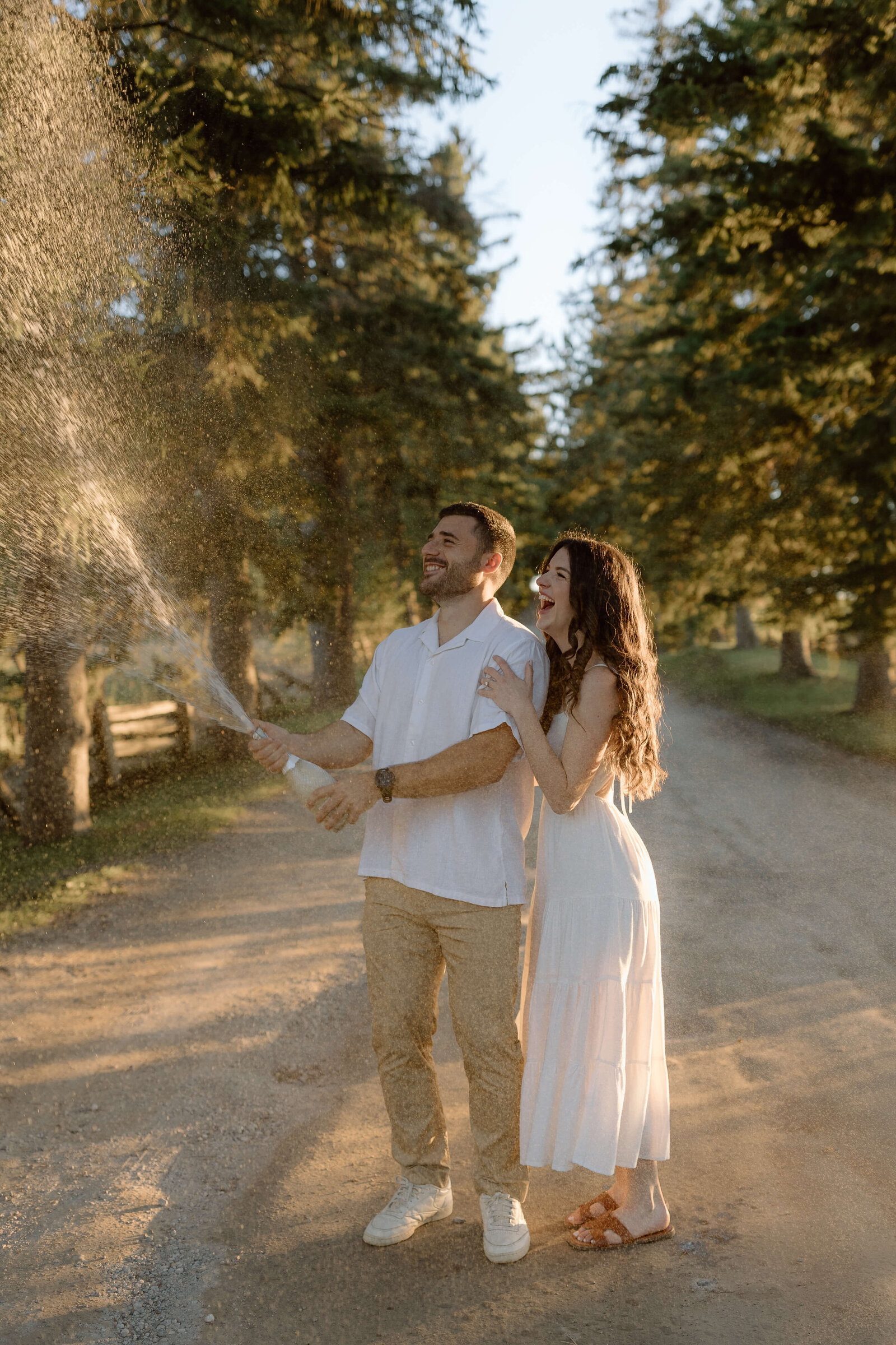 A couple popping a bottle of champagne for their engagement session