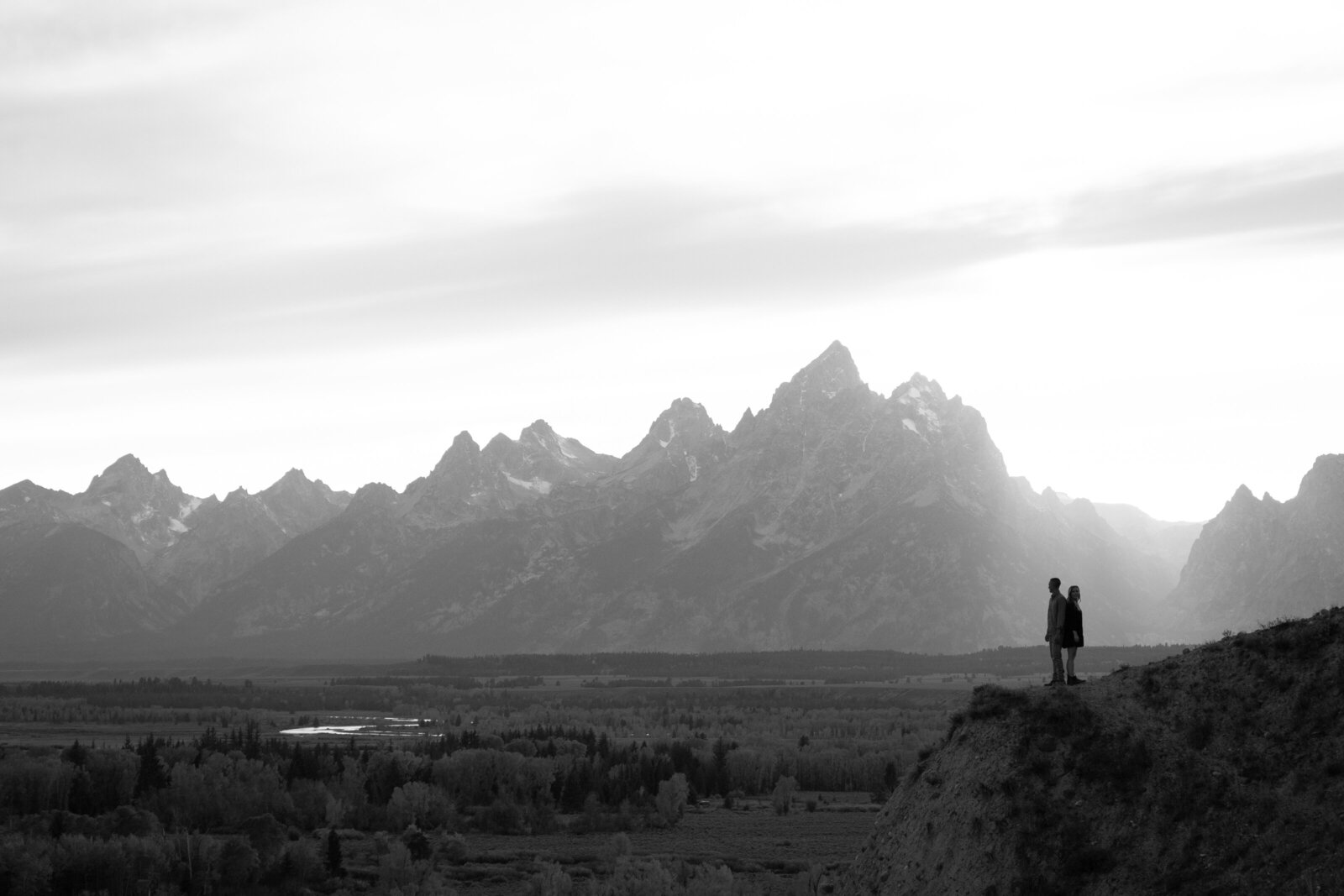 Silhouettes of a couple in front of the Tetons.